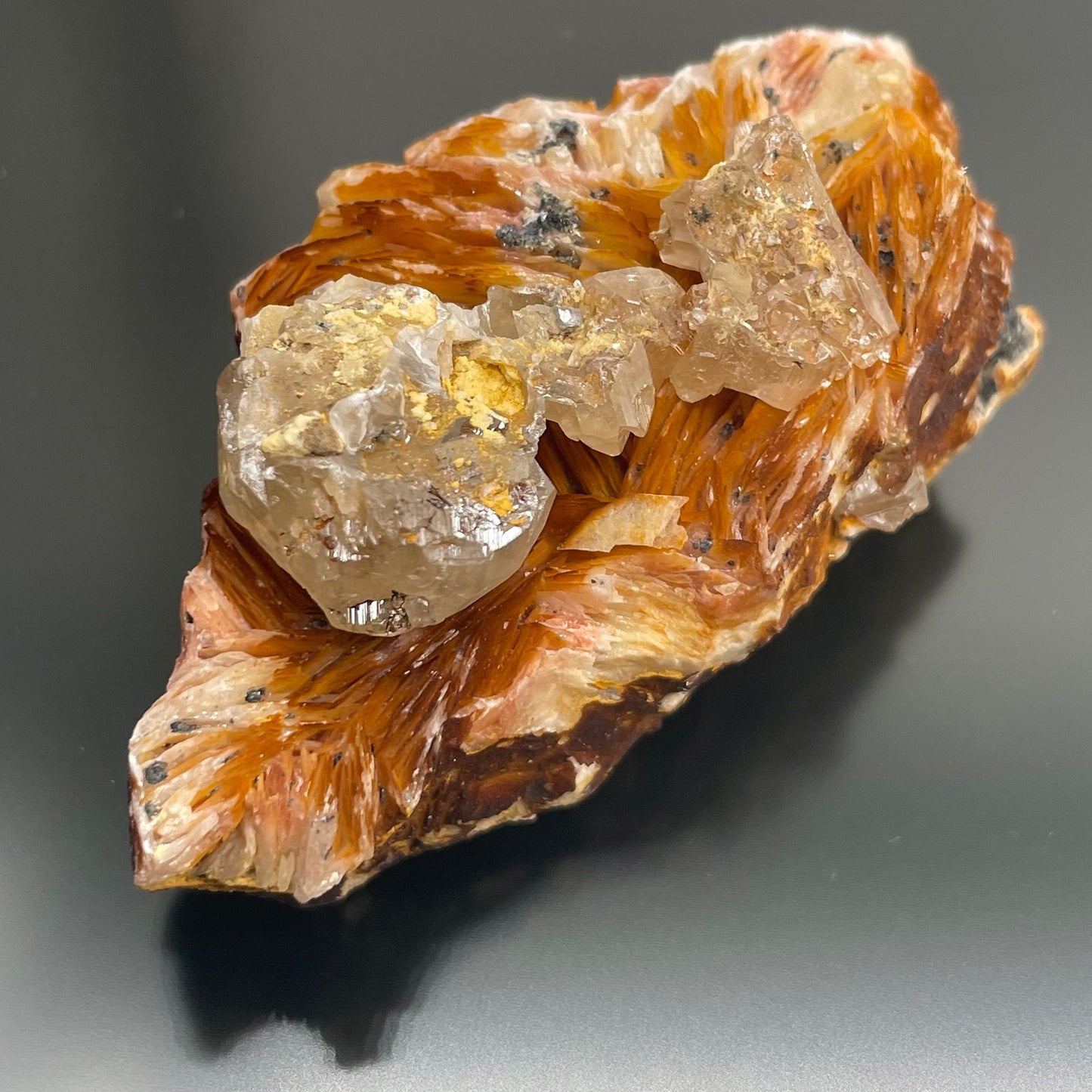 Ein roher Barit-Sericit-Kristall mit orangefarbenen und weißen Schichten und klaren Kristallen.