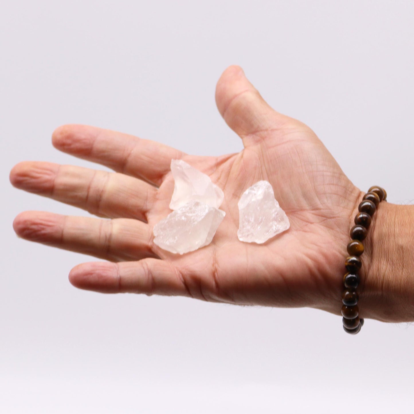 Hand holding rough clear quartz crystals.