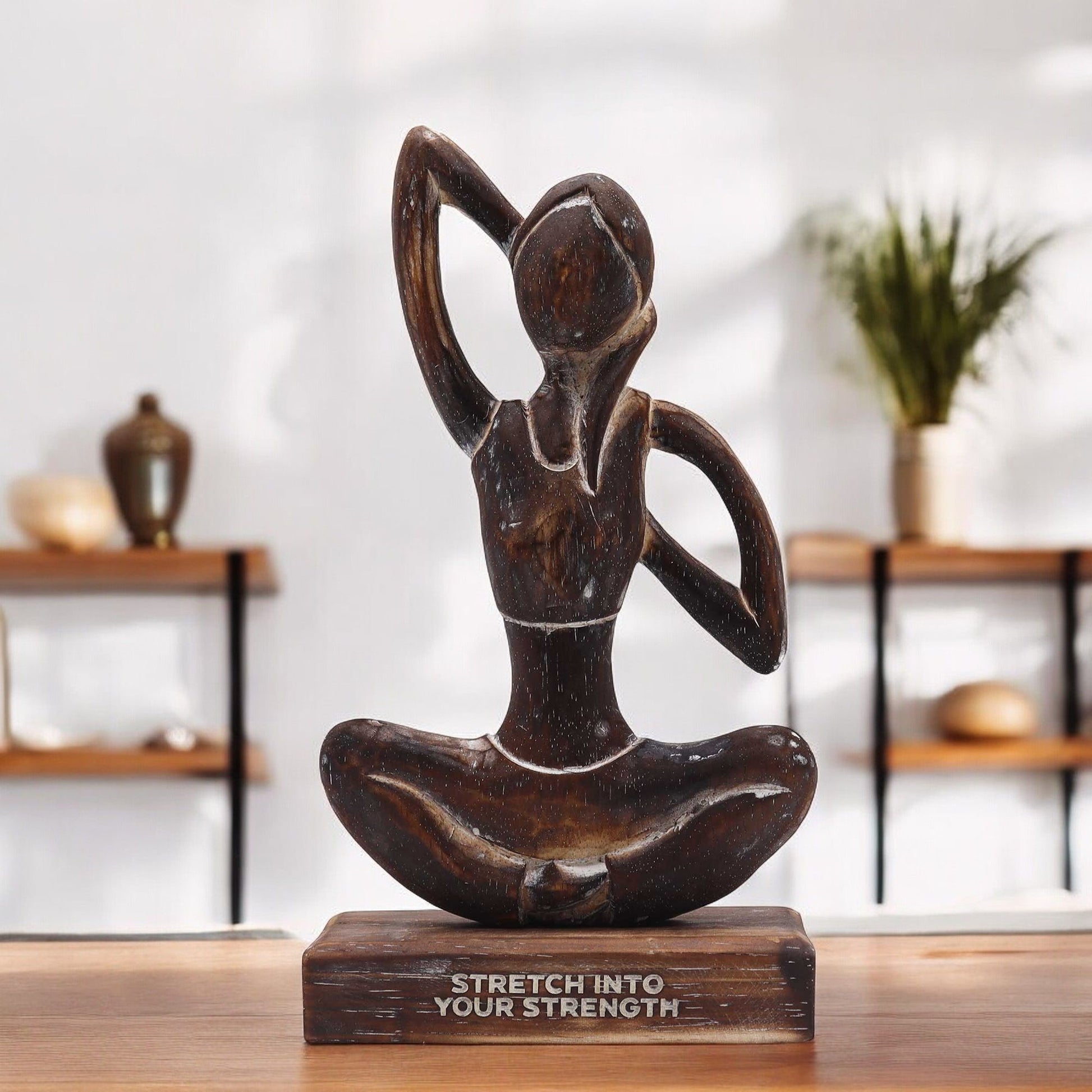 Yoga-Holzfigur mit der Aufschrift "Stretch into Your Strength".