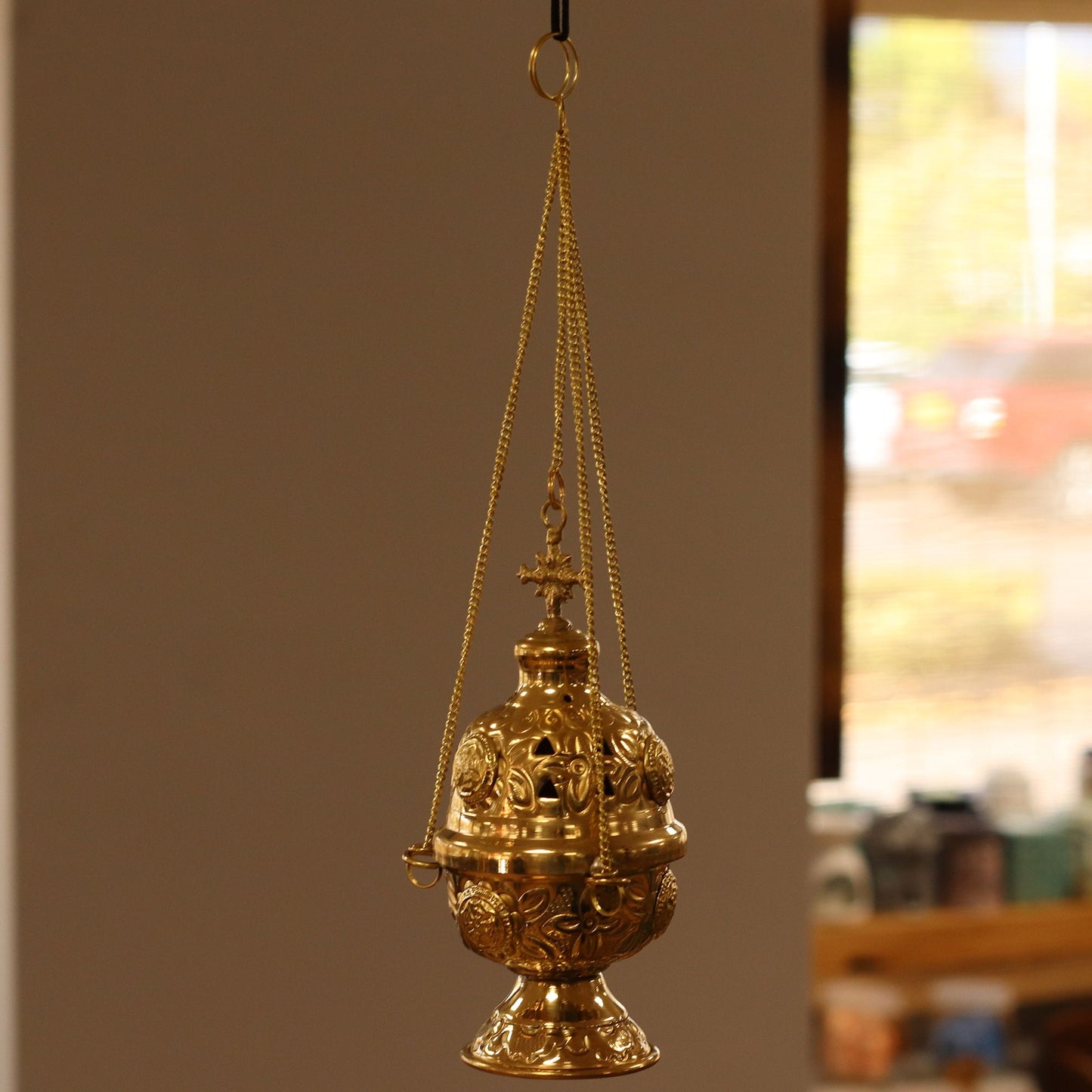 Hanging brass incense burner with ornate carvings and a cross finial.