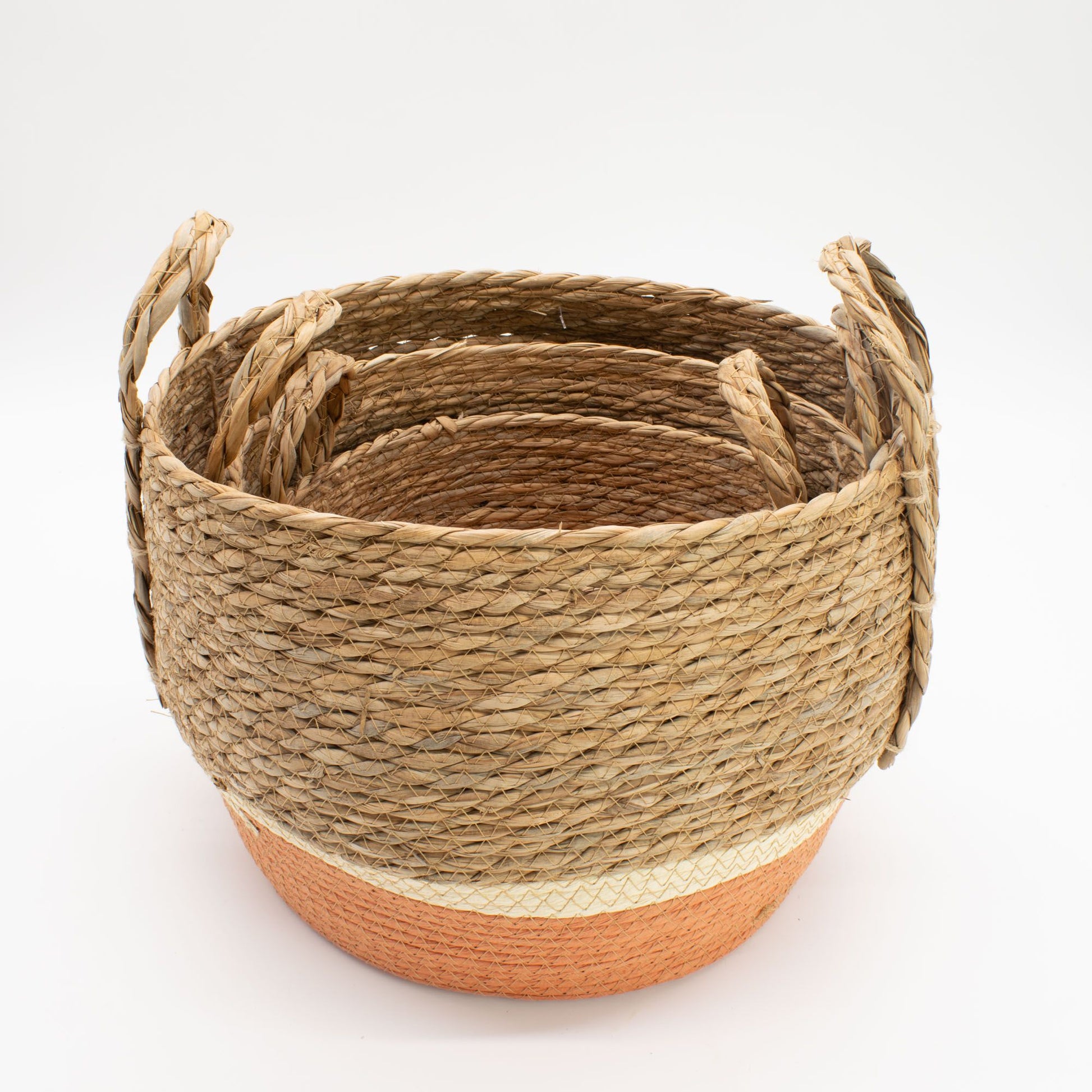 Set of 3 natural and orange woven straw and seagrass baskets with handles.
