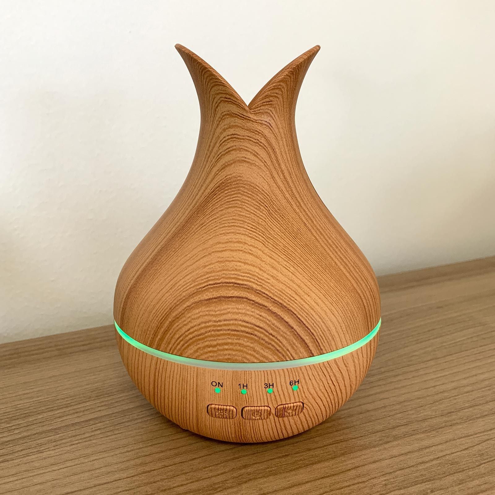 Wooden-look essential oil diffuser with timer settings and green LED light.
