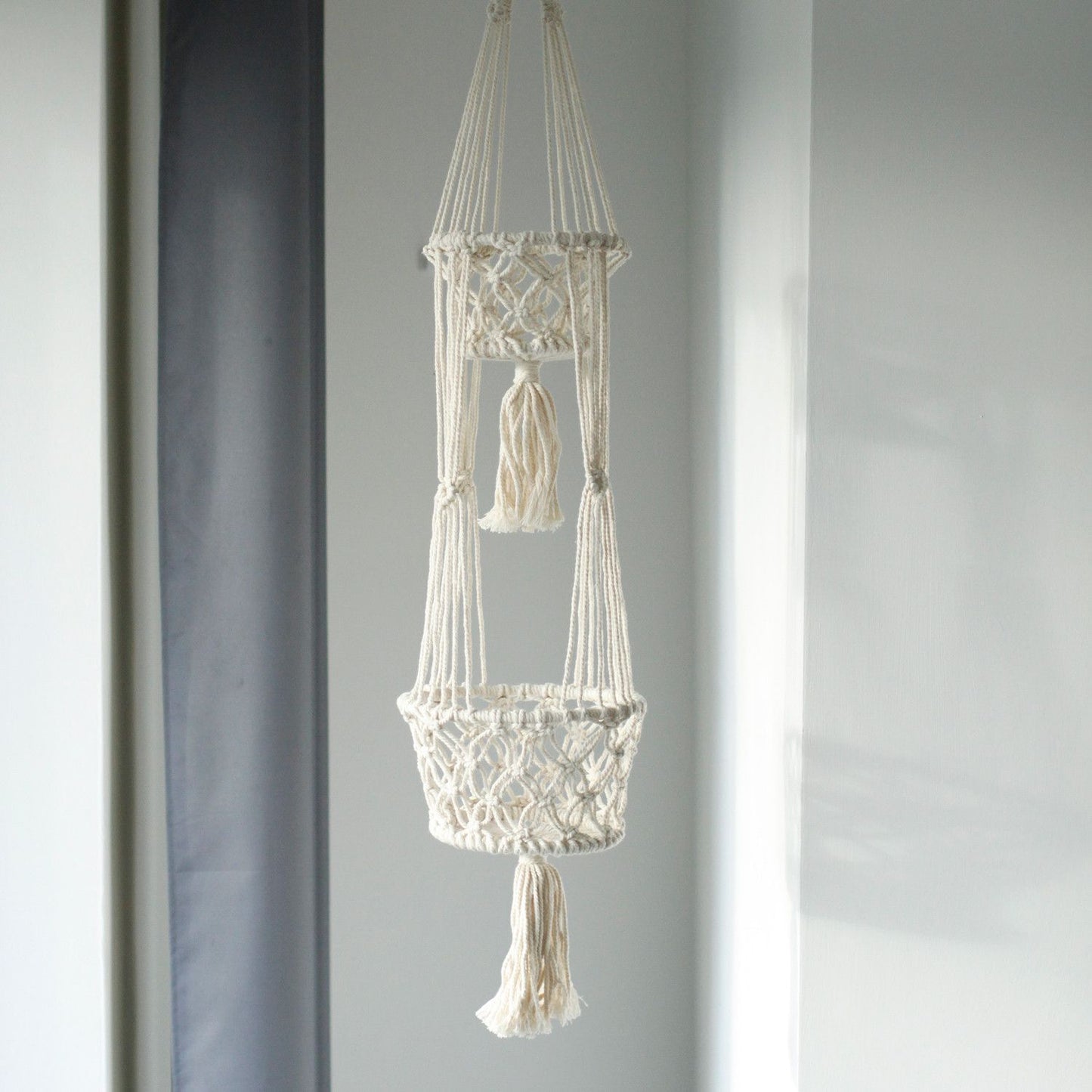 Doppelter Makramee-Blumentopfhalter aus Baumwolle mit Quasten.