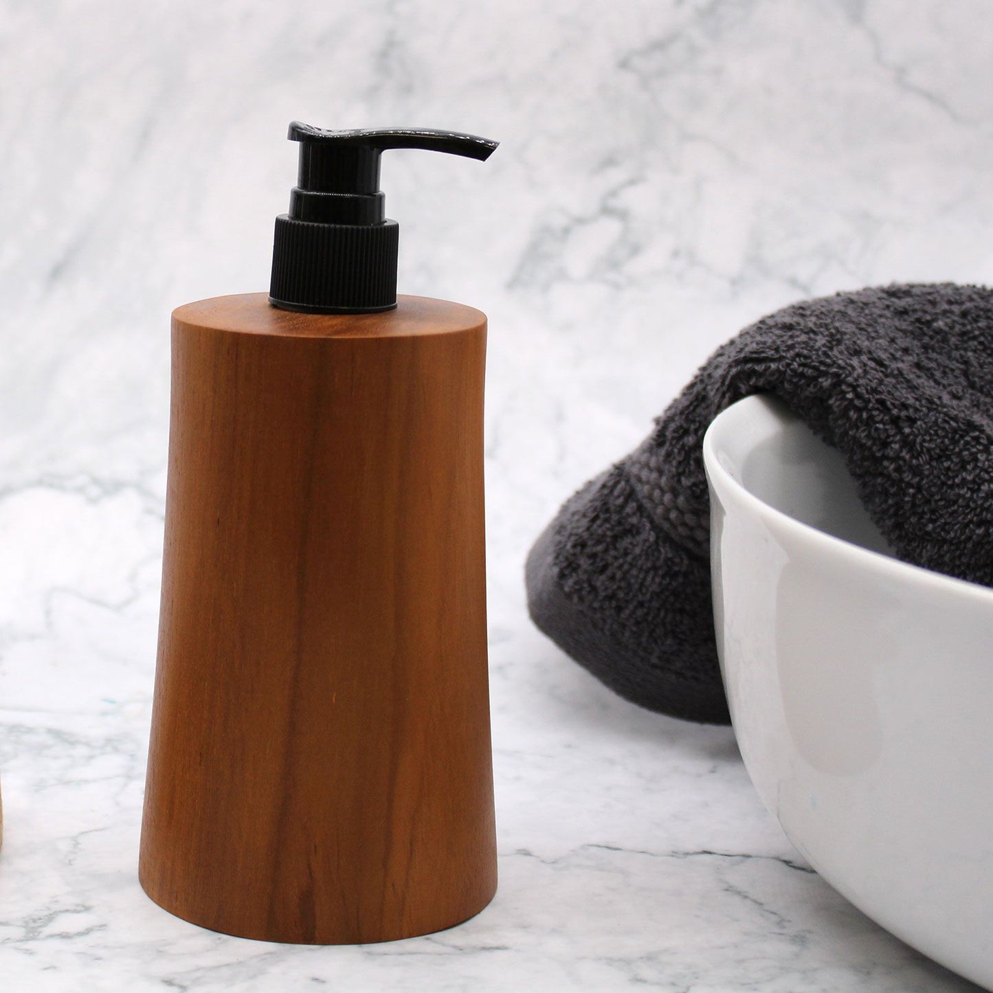 Natural teakwood soap dispenser with a black pump on a marble surface.