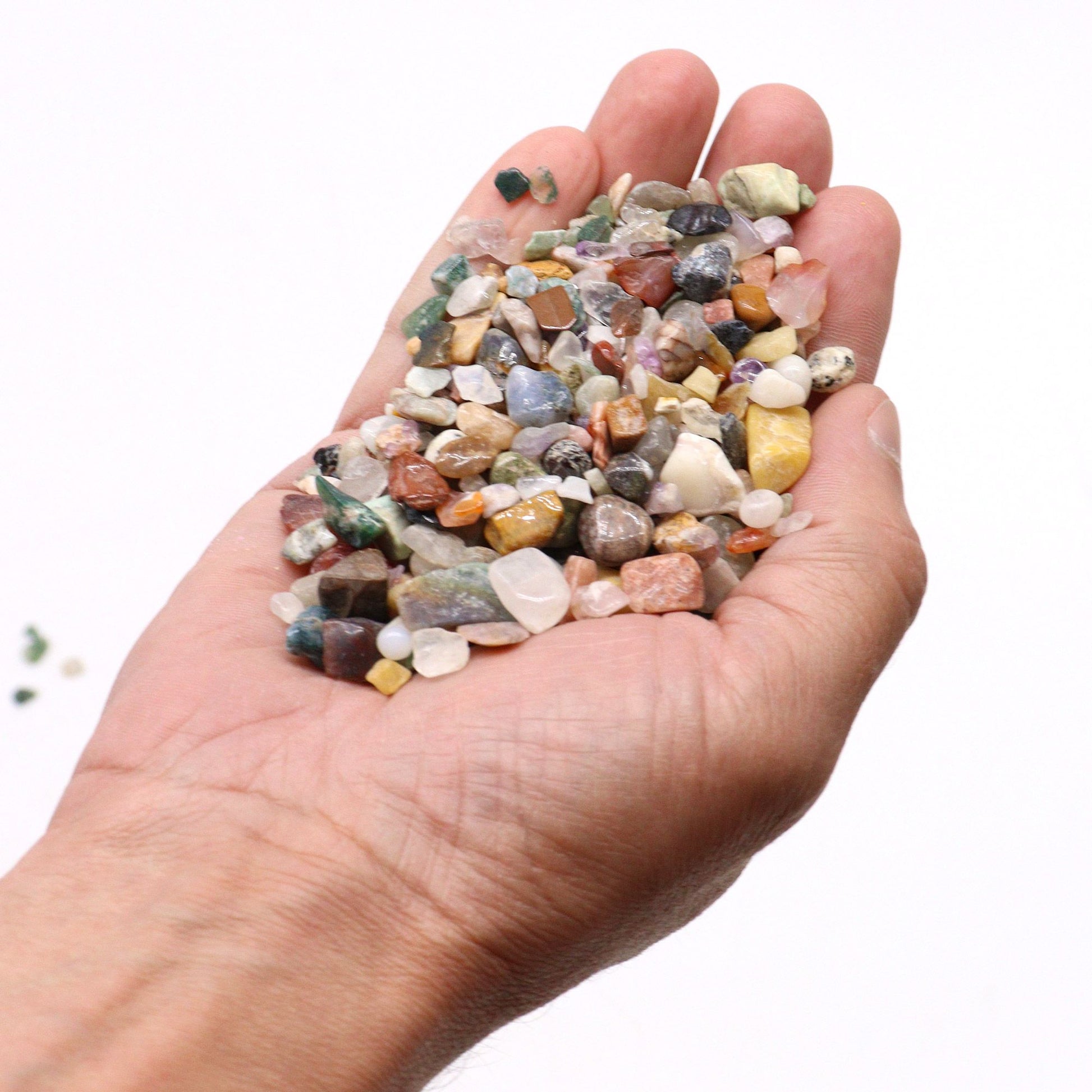 Eine Hand hält eine Mischung aus bunten, getrommelten Edelsteinchips.