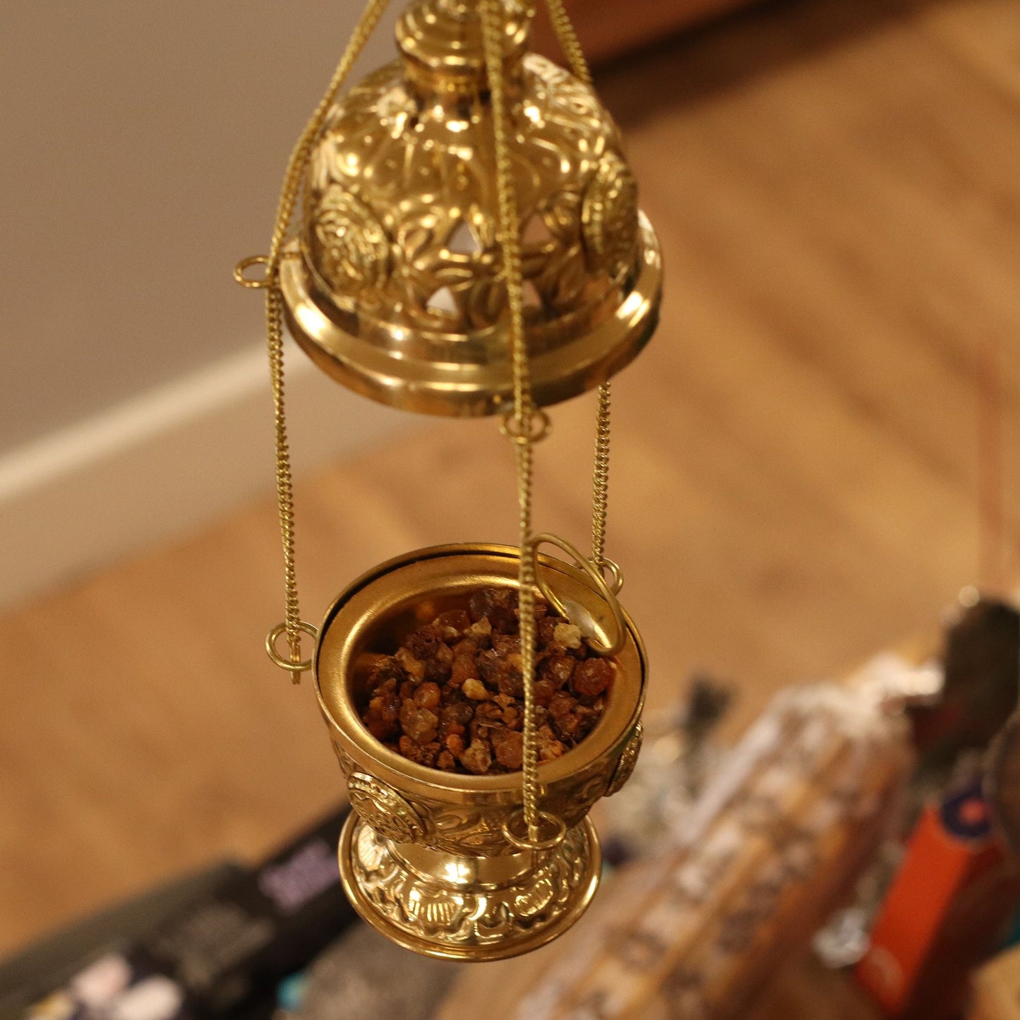 Hanging brass incense burner filled with incense pieces.