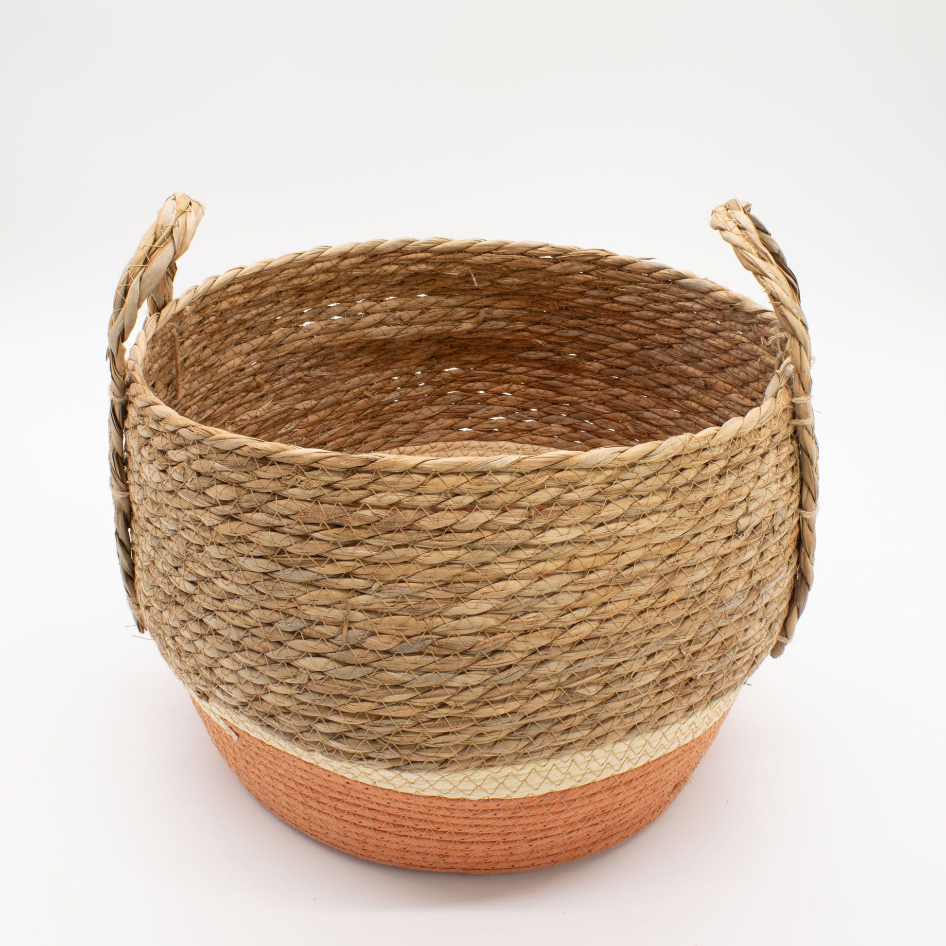 A round straw and seagrass basket with handles and an orange base.