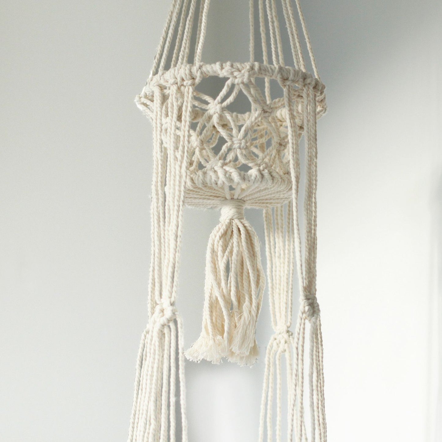 Handgefertigter Makramee-Doppelblumentopfhalter aus Baumwolle mit Quaste.