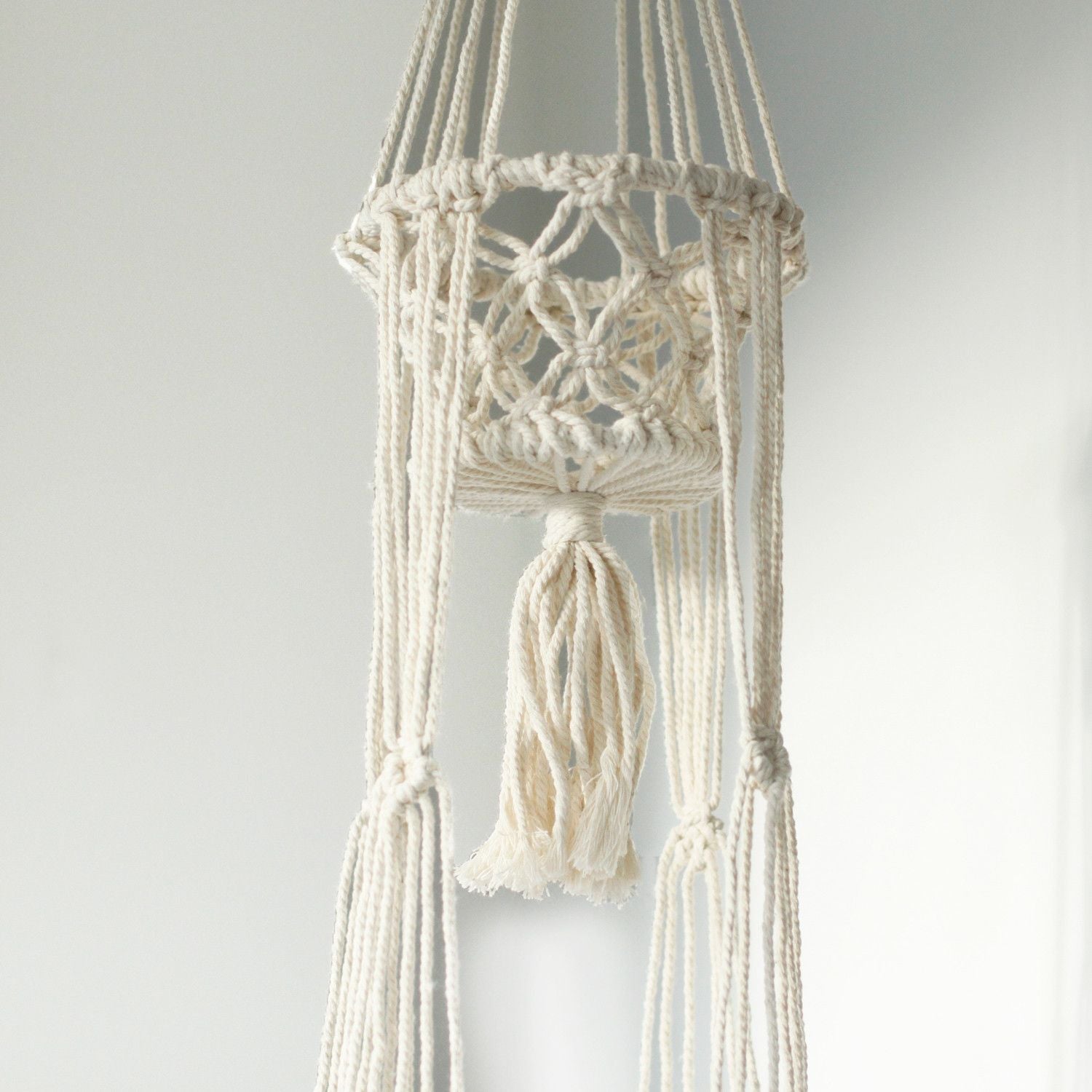 Handgefertigter Makramee-Doppelblumentopfhalter aus Baumwolle mit Quaste.