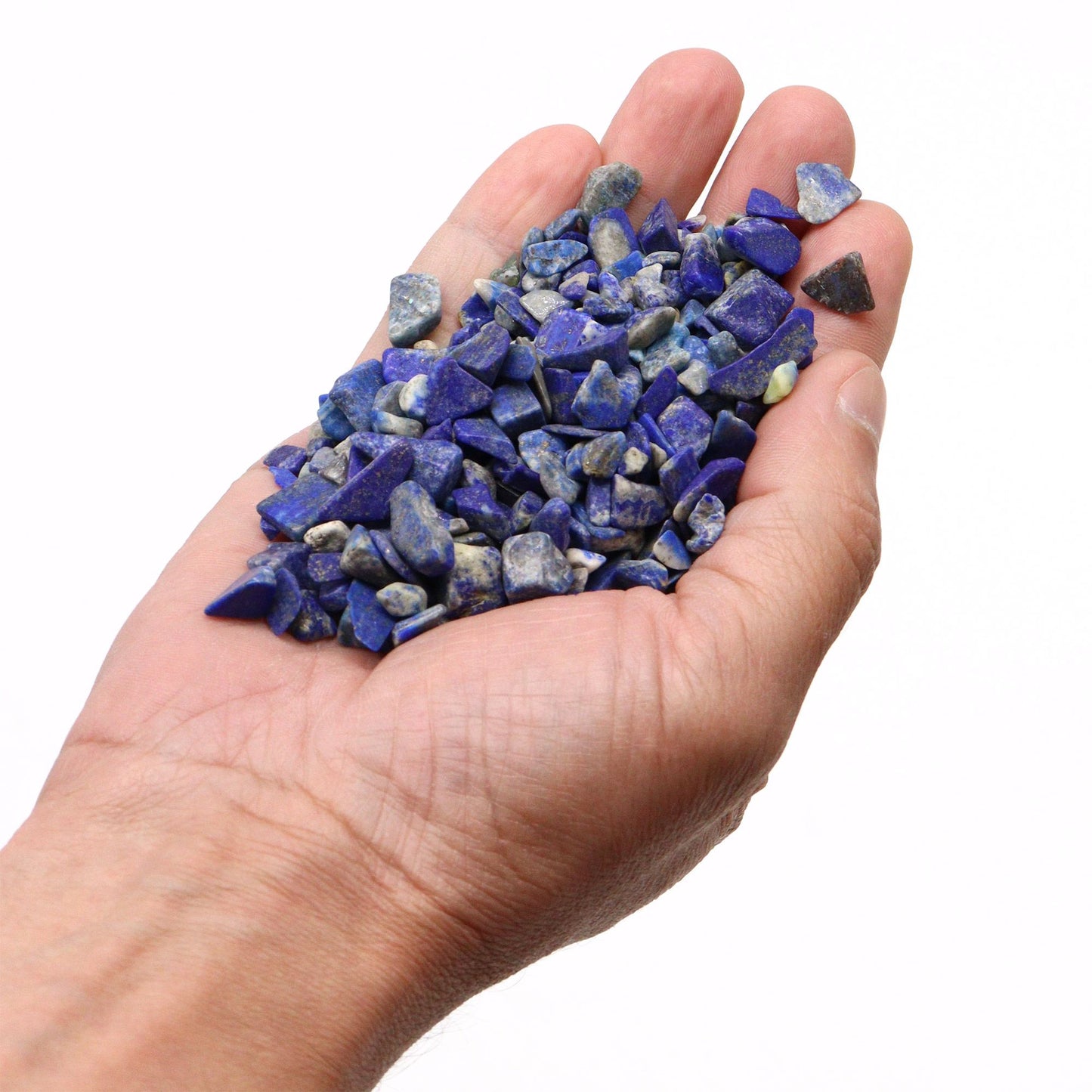 Hand holding tumbled lapis lazuli chips.