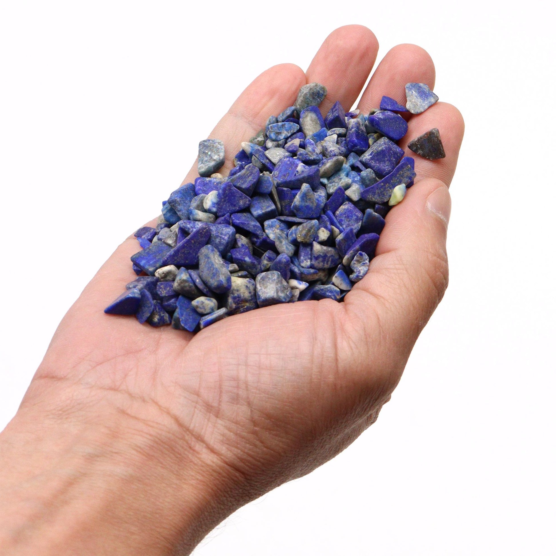 Hand holding tumbled lapis lazuli chips.