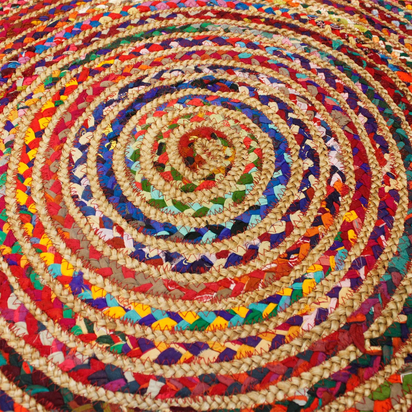 Runder Juteteppich mit recycelter Baumwolle in bunten Spiralmustern.