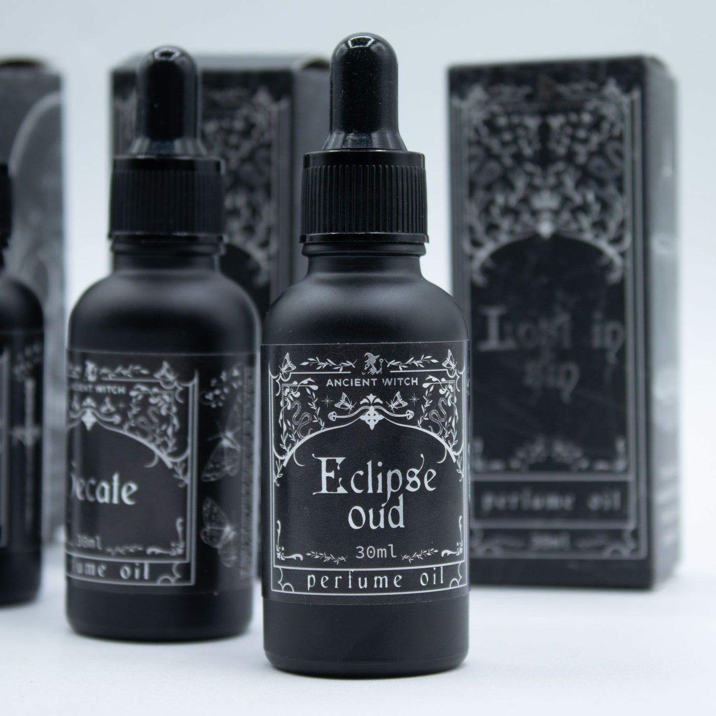Black perfume oil bottles with ornate labels, including "Eclipse Oud".