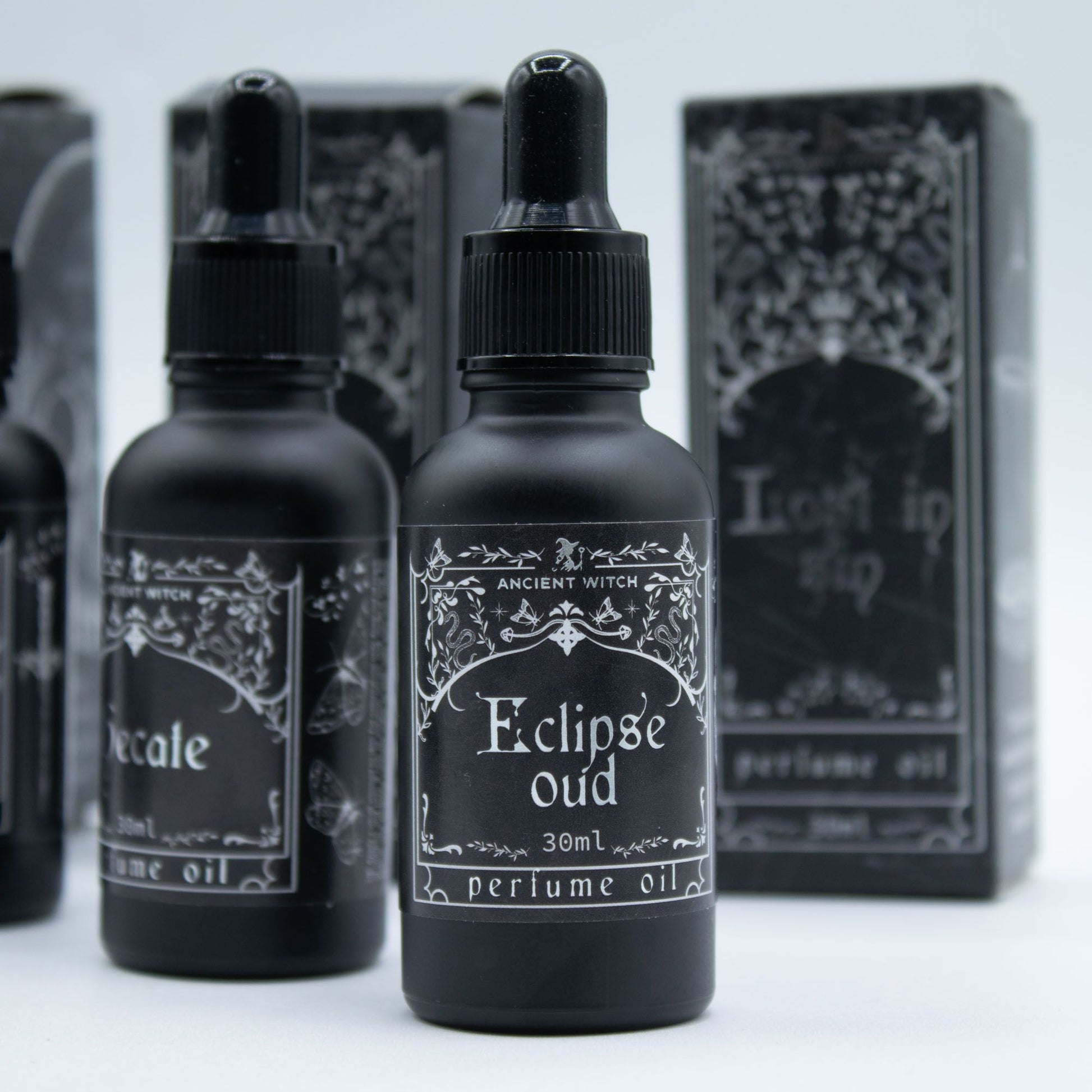 Black perfume oil bottles with ornate labels, including "Eclipse Oud".