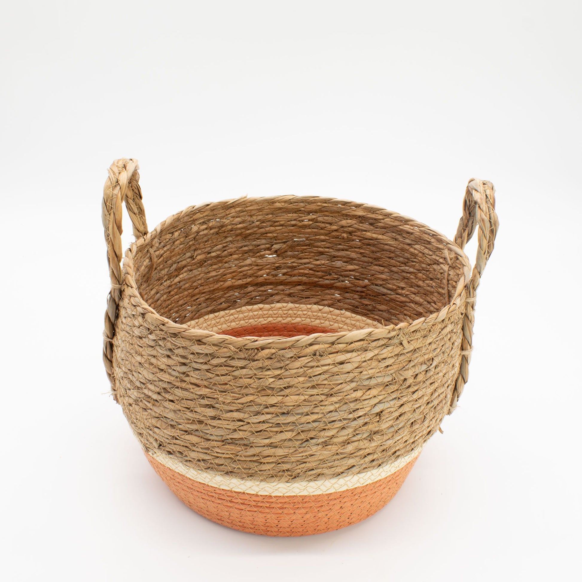 A round woven straw and seagrass basket with handles and an orange base.