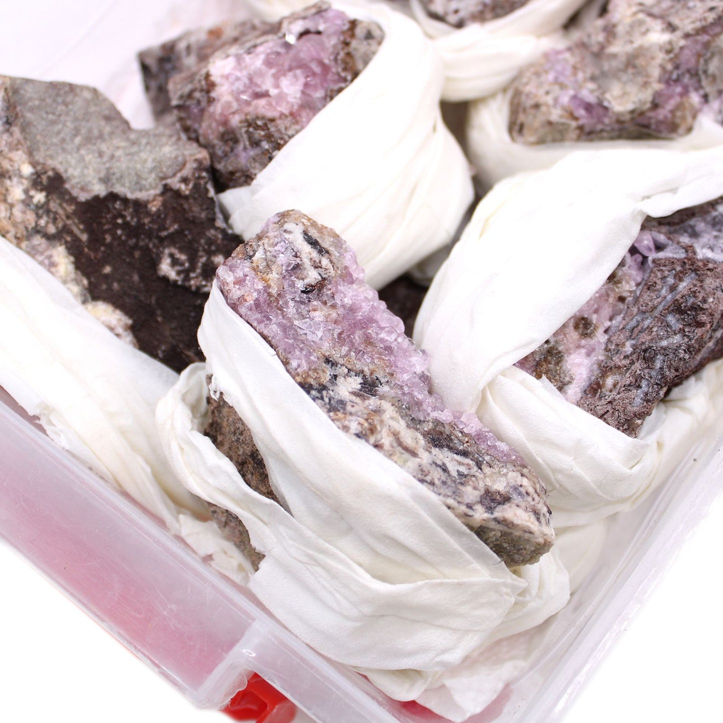 Cobalt-Calcit Rohsteine in Rosa-Violett, einzeln in weißes Tuch gewickelt.