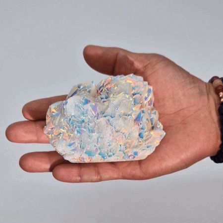 Großer Angel-Aura-Quarz-Cluster in einer Hand mit schillernden Farben.