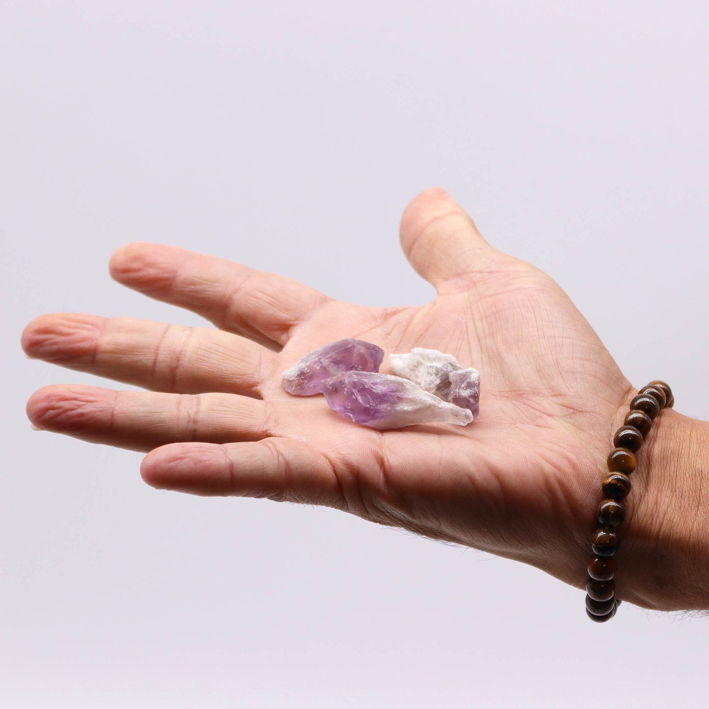 Hand holding raw amethyst crystal points.