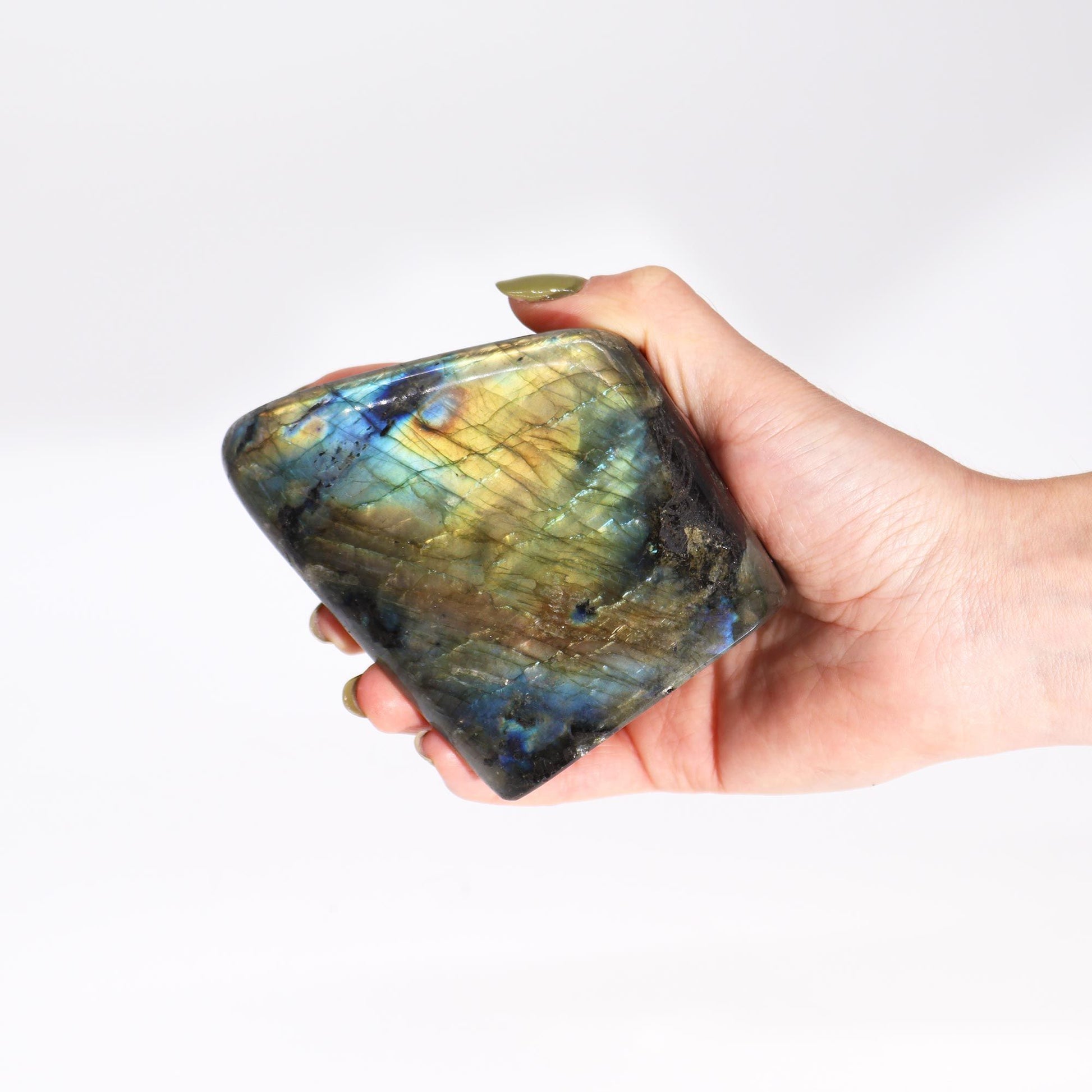 Hand hält einen großen, facettierten Labradorit mit blau-grünem Schimmer.
