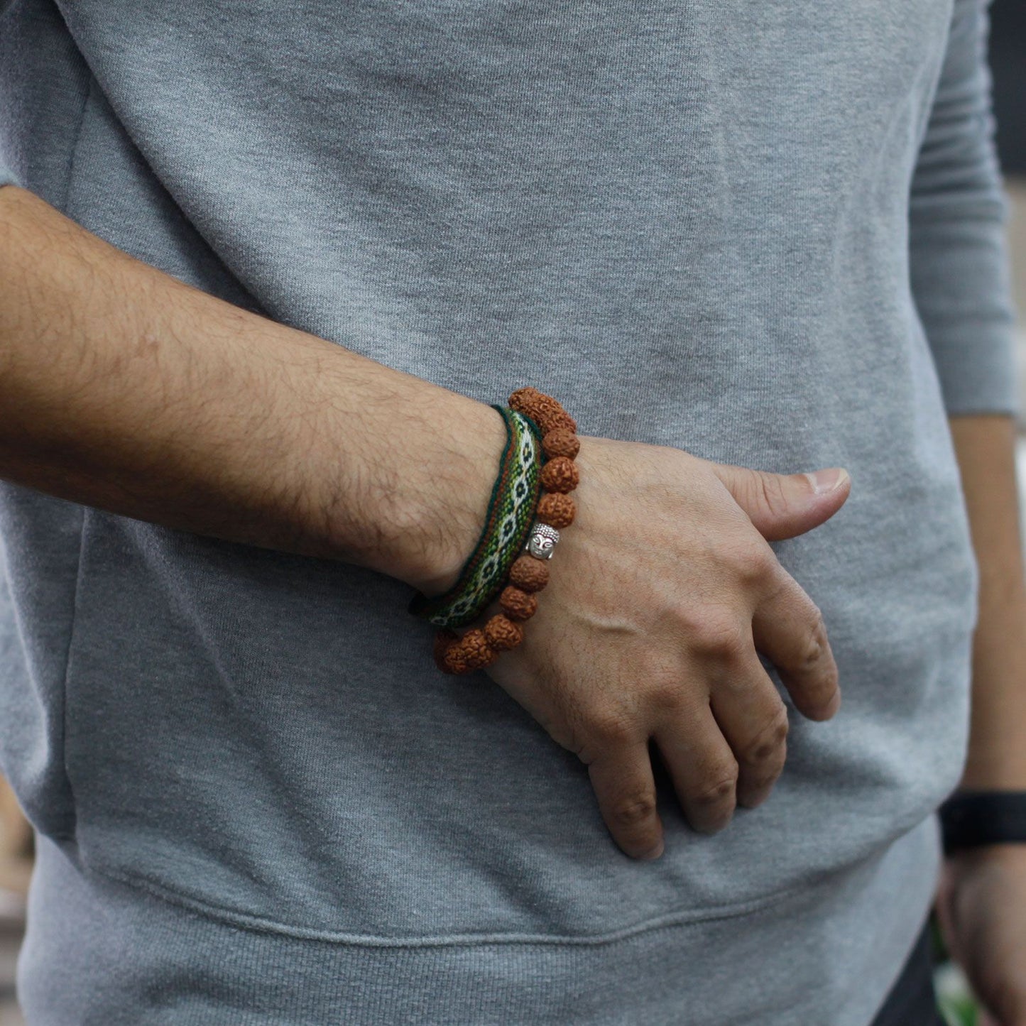 Brown Rudraksha mala bracelet with a Buddha charm and a woven band.
