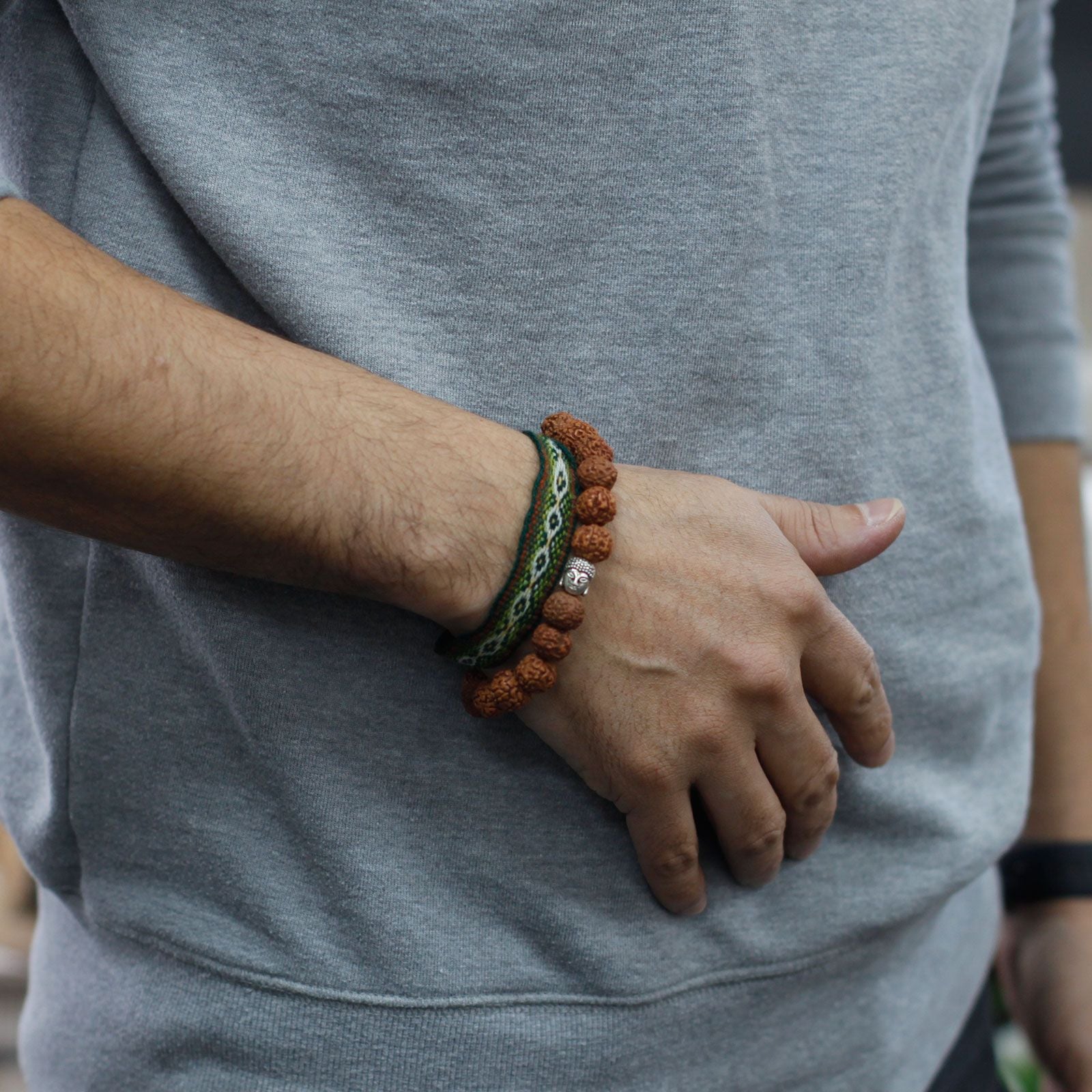 Brown Rudraksha mala bracelet with a Buddha charm and a woven band.