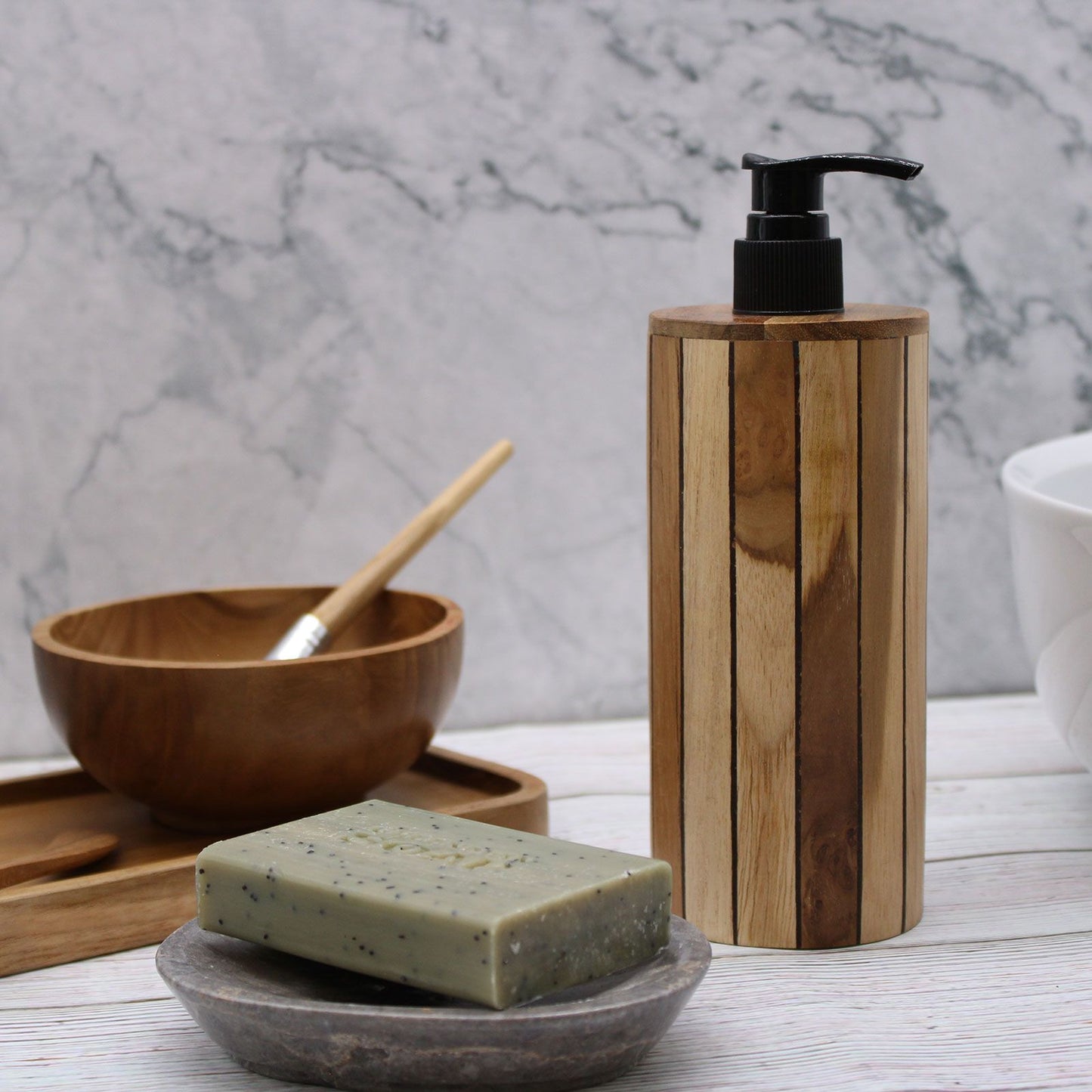 Natural teakwood soap dispenser with a black pump next to a bar of soap.