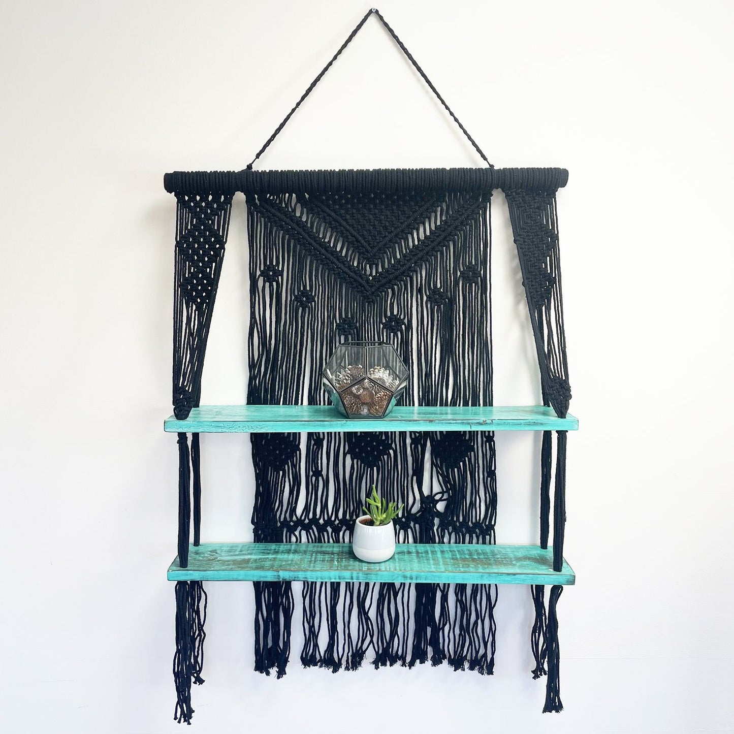 Dekoratives Macrame-Hängeregal im Bohostil mit zwei Holzablagen.