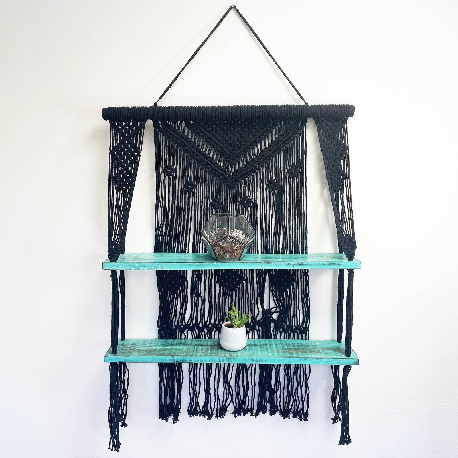 Dekoratives Macrame-Hängeregal im Bohostil mit zwei Holzablagen.