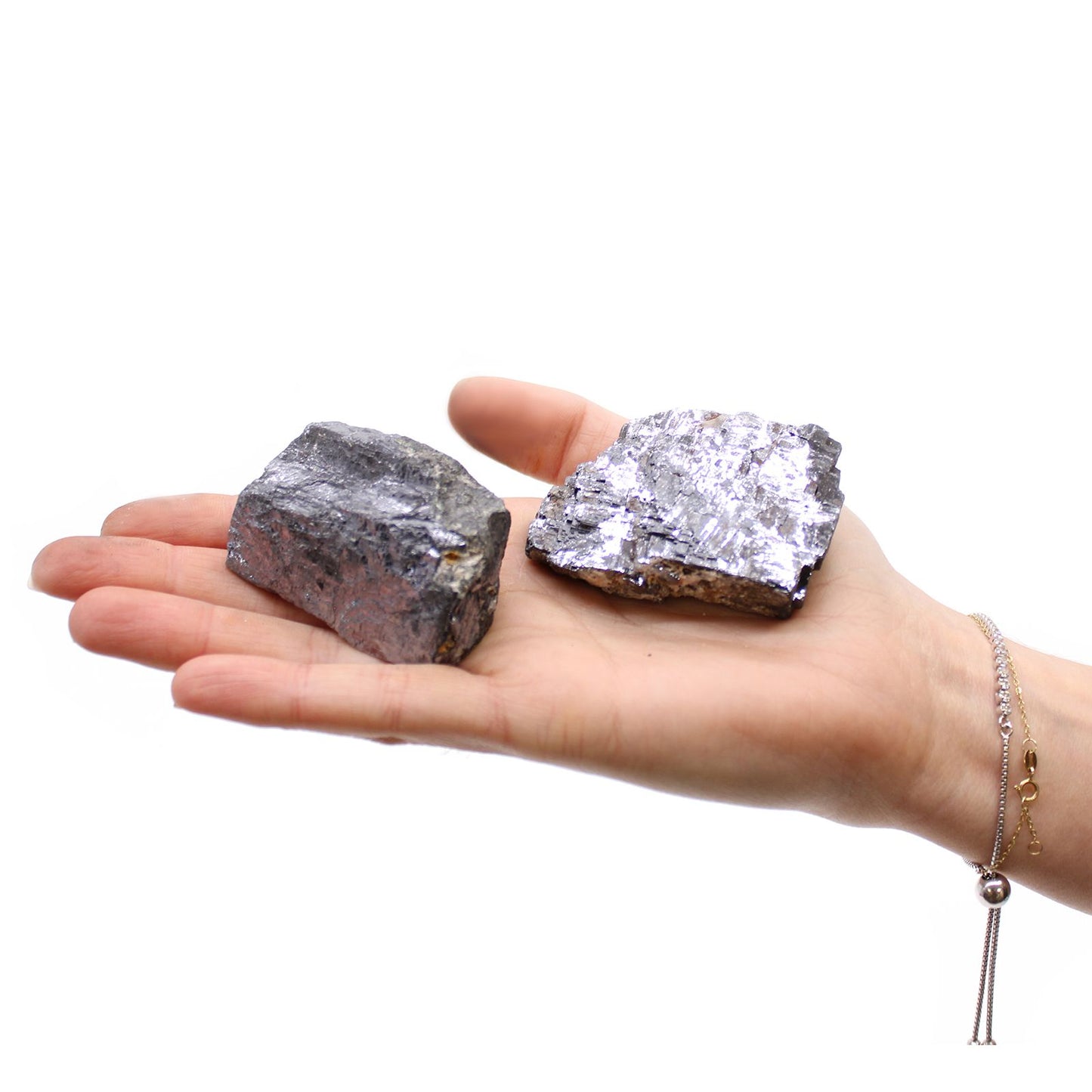 Zwei rohe Galena-Mineralien mit metallischem Glanz liegen in einer Hand.