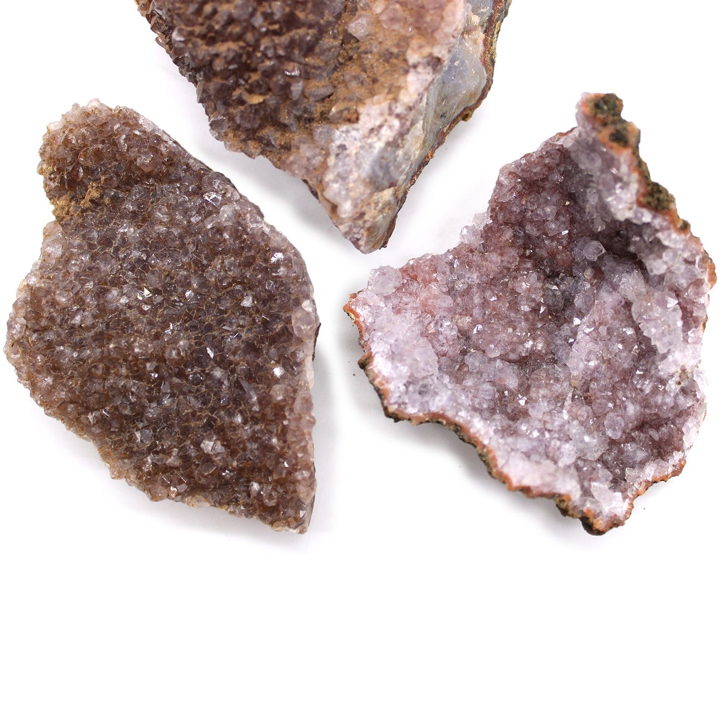 Drei rohe Amethyst-Geoden mit violetten Kristallen auf weißem Hintergrund.