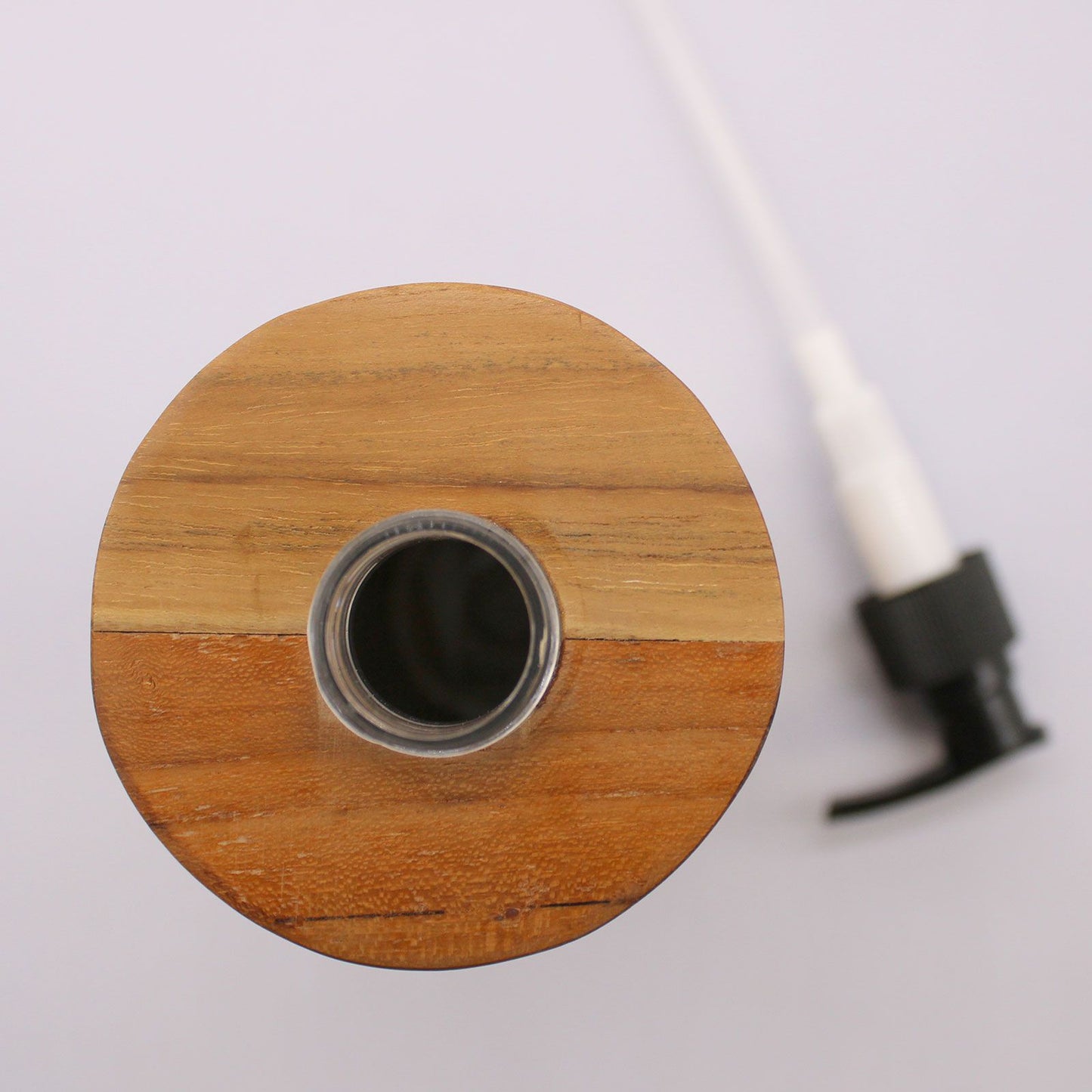 Round natural teakwood soap dispenser with a pump.