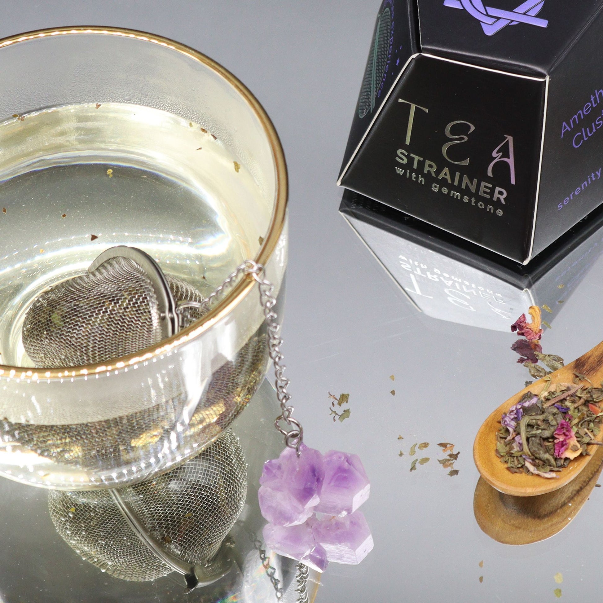 Edelsteinteesieb mit Amethyst und Edelstahl-Infuser in einem Glas.