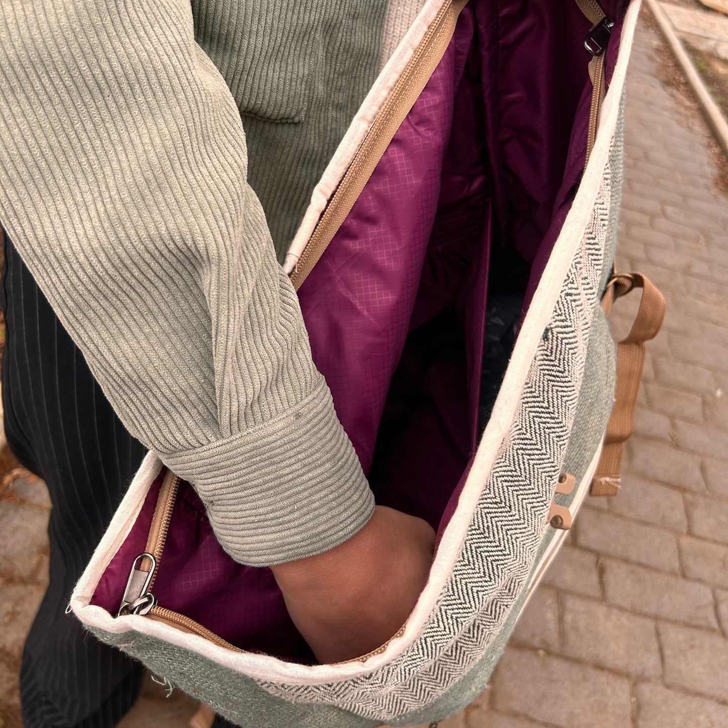 Ein Hanf-Trekkingrucksack in Salbeigrün mit offenem Hauptfach und lila Innenfutter.