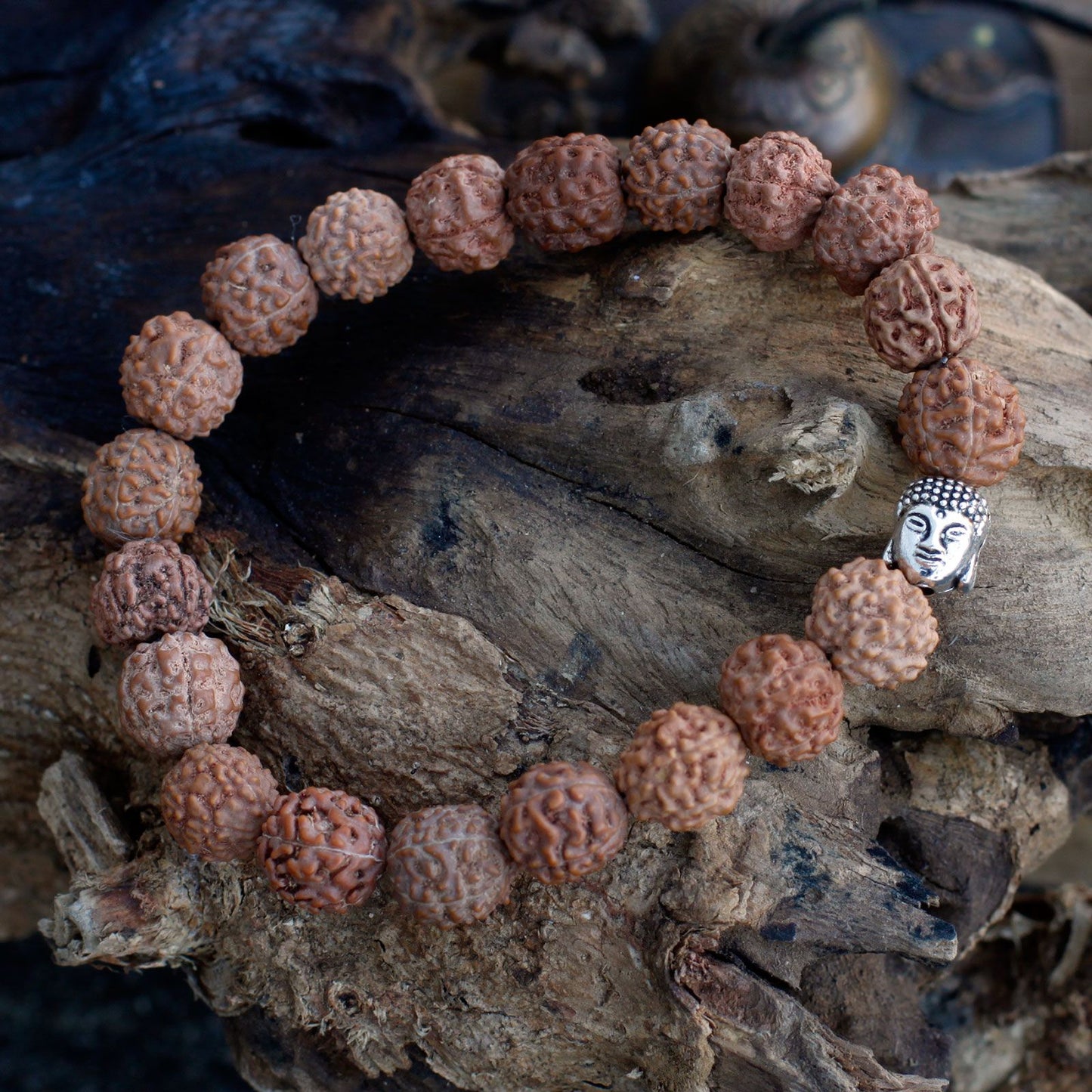 Rudraksha bangle mala with a Buddha charm on a wooden surface.