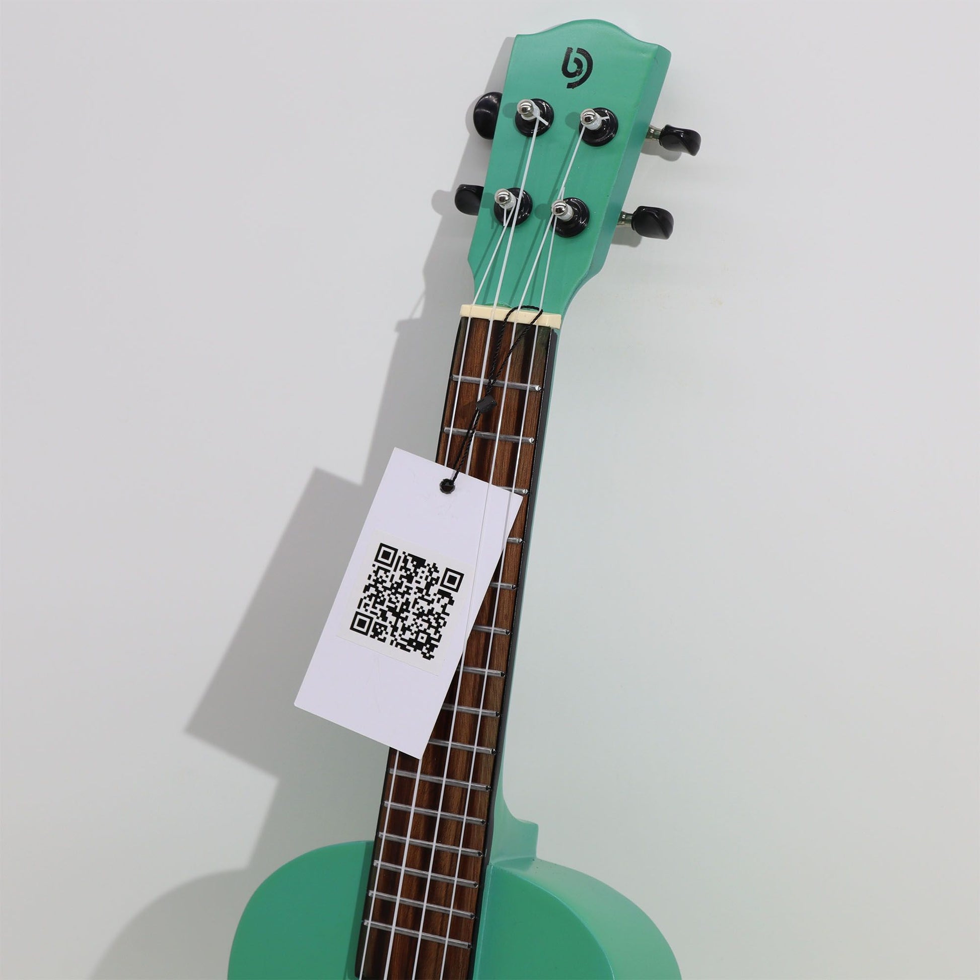 Türkisblaue Ukulele mit schwarzem Logo und QR-Code-Anhänger.