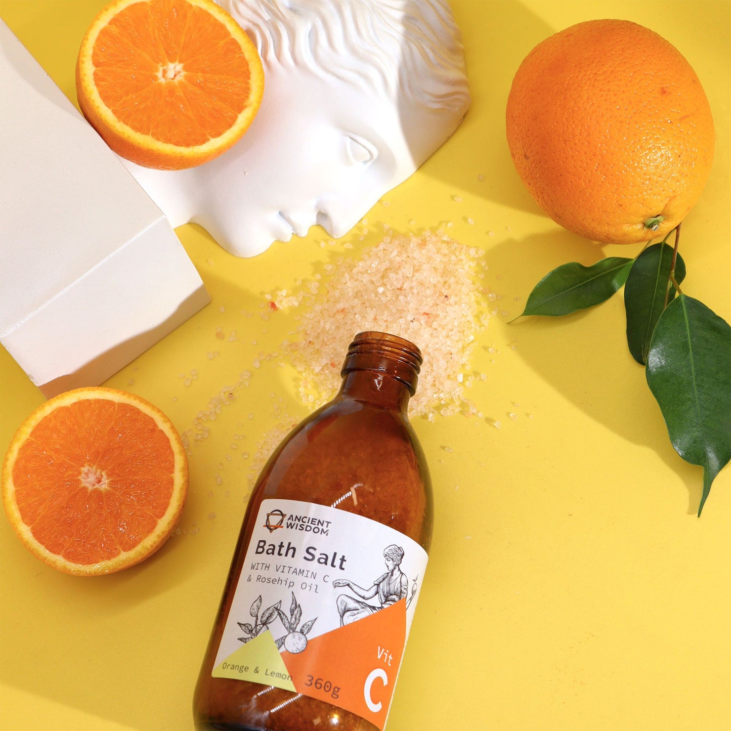 Braune Glasflasche mit Vitamin C Badesalz, Orangen und Zitronen.