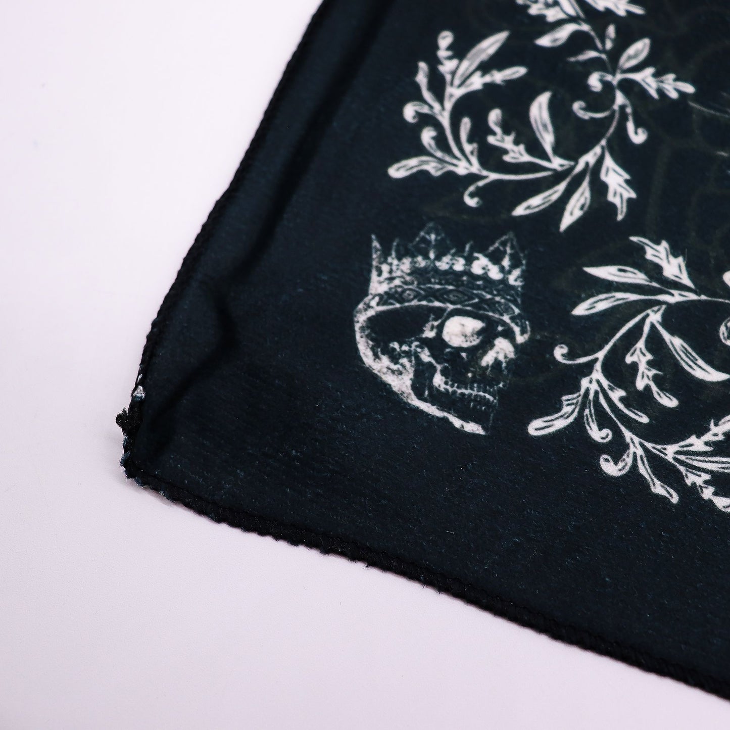 Black tarot cloth with a white skull wearing a crown and floral design.