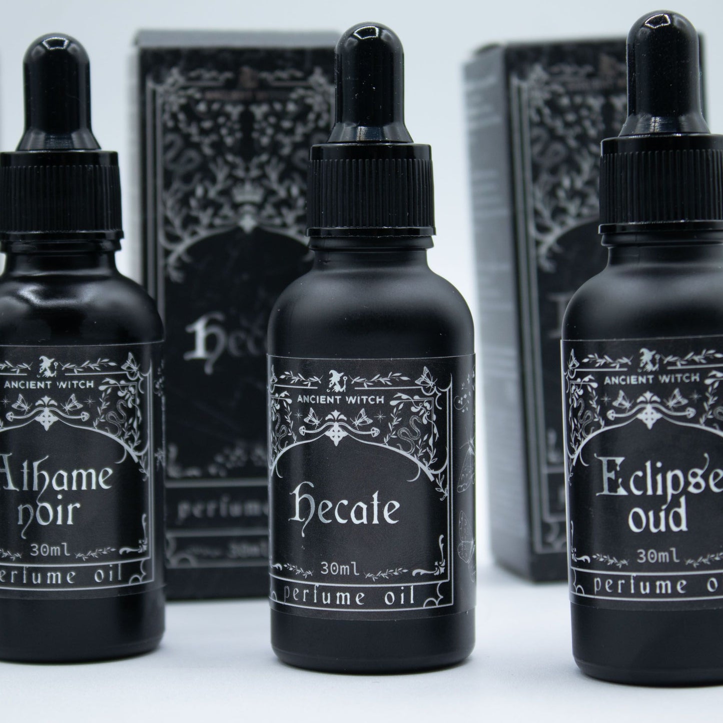 Three black bottles of Ancient Witch perfume oil with ornate labels.