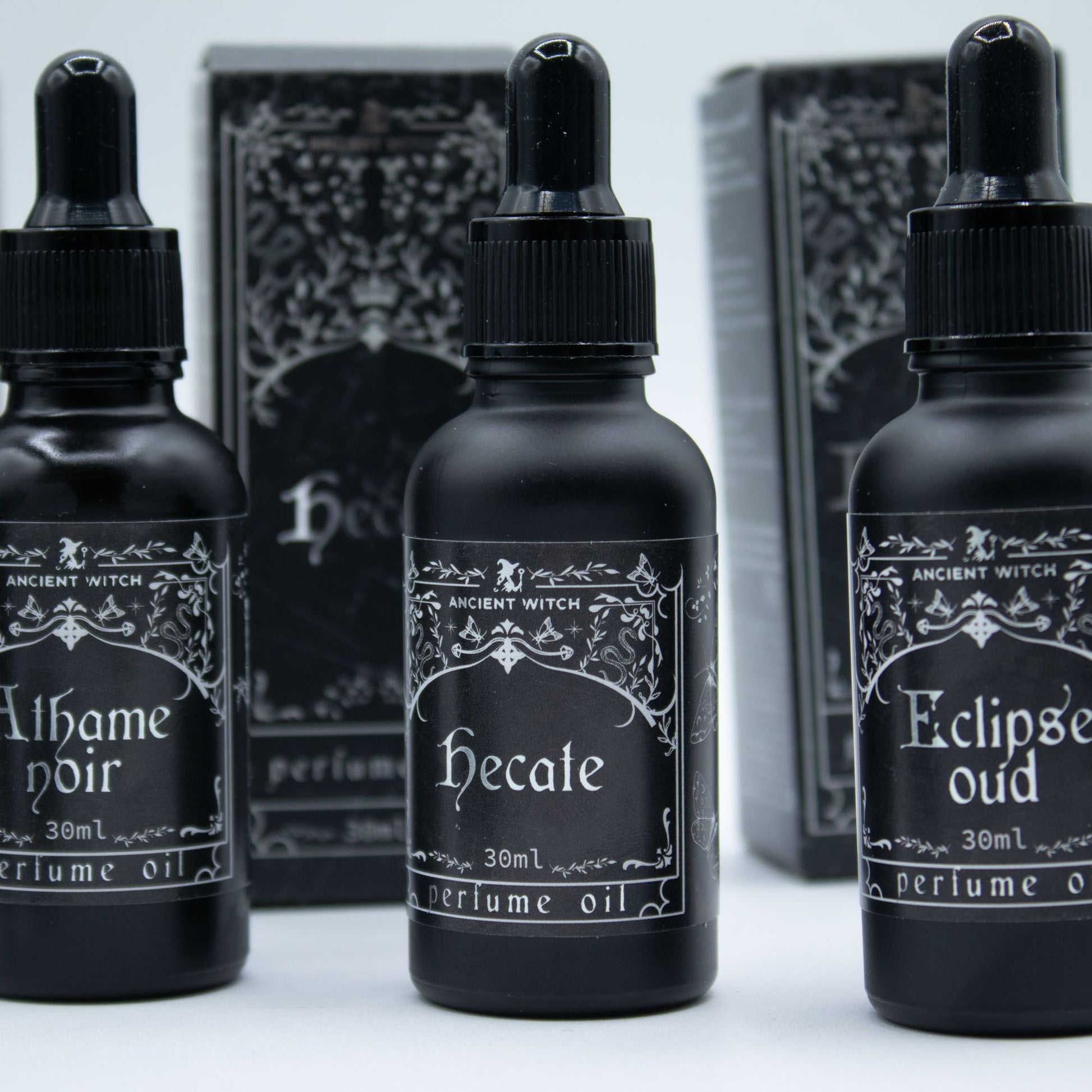Three black bottles of Ancient Witch perfume oil with ornate labels.