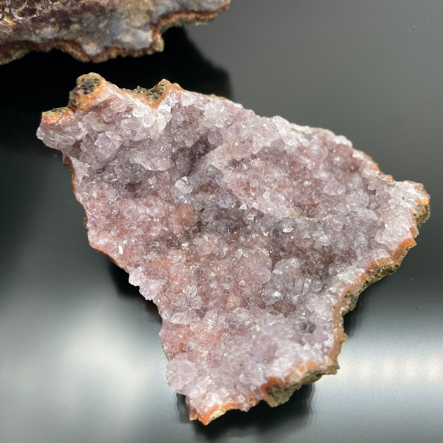 Ein Stück roher Amethyst mit violetten Kristallen auf einer braunen Basis.