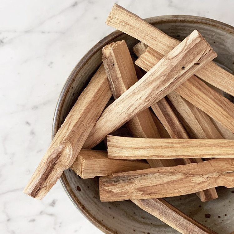 Palo Santo Holzstäbchen in einer Schale auf Marmoruntergrund.