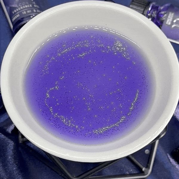 Violettes Duftöl mit Glitzer in einer weißen Schale.