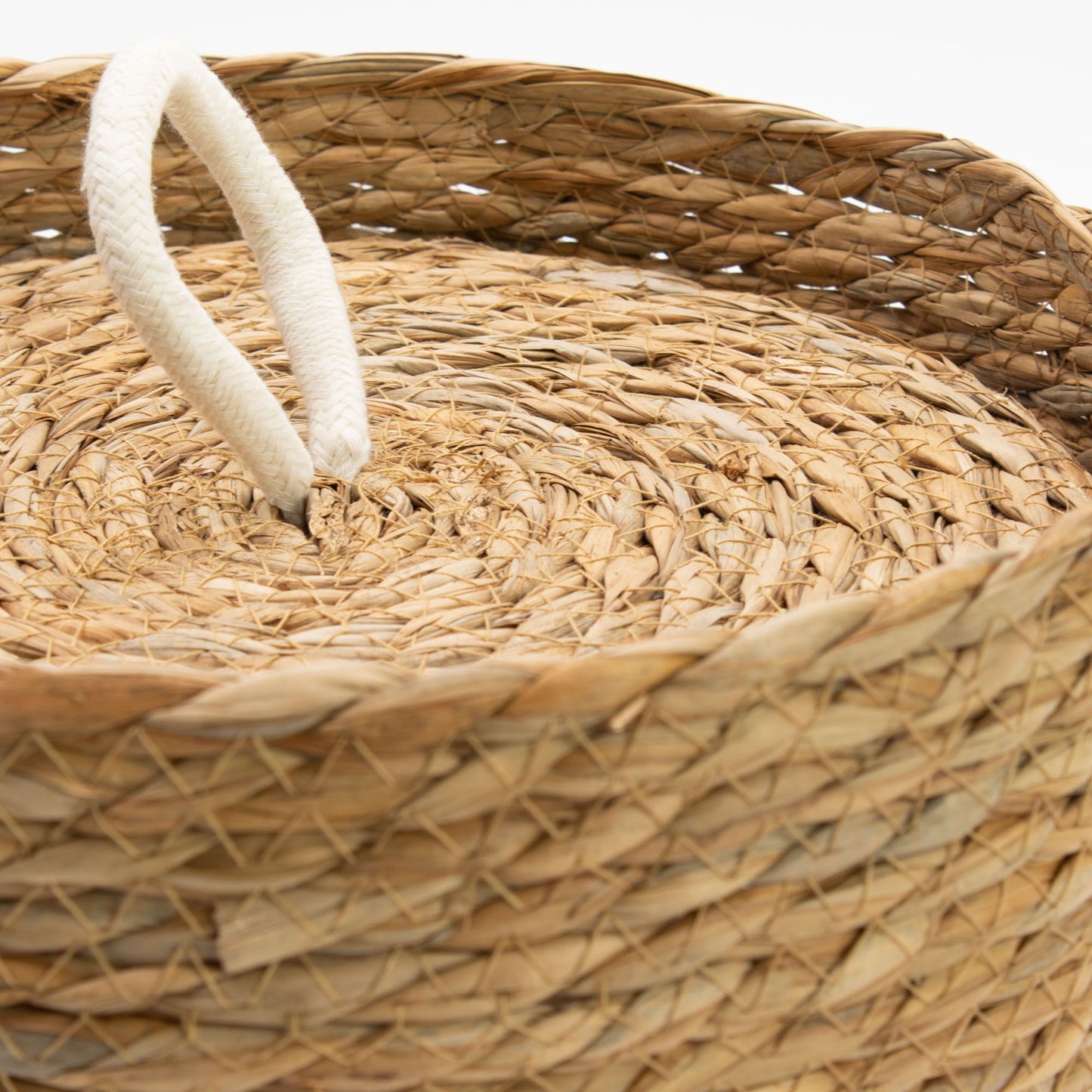 A natural woven seagrass basket with a white rope handle.