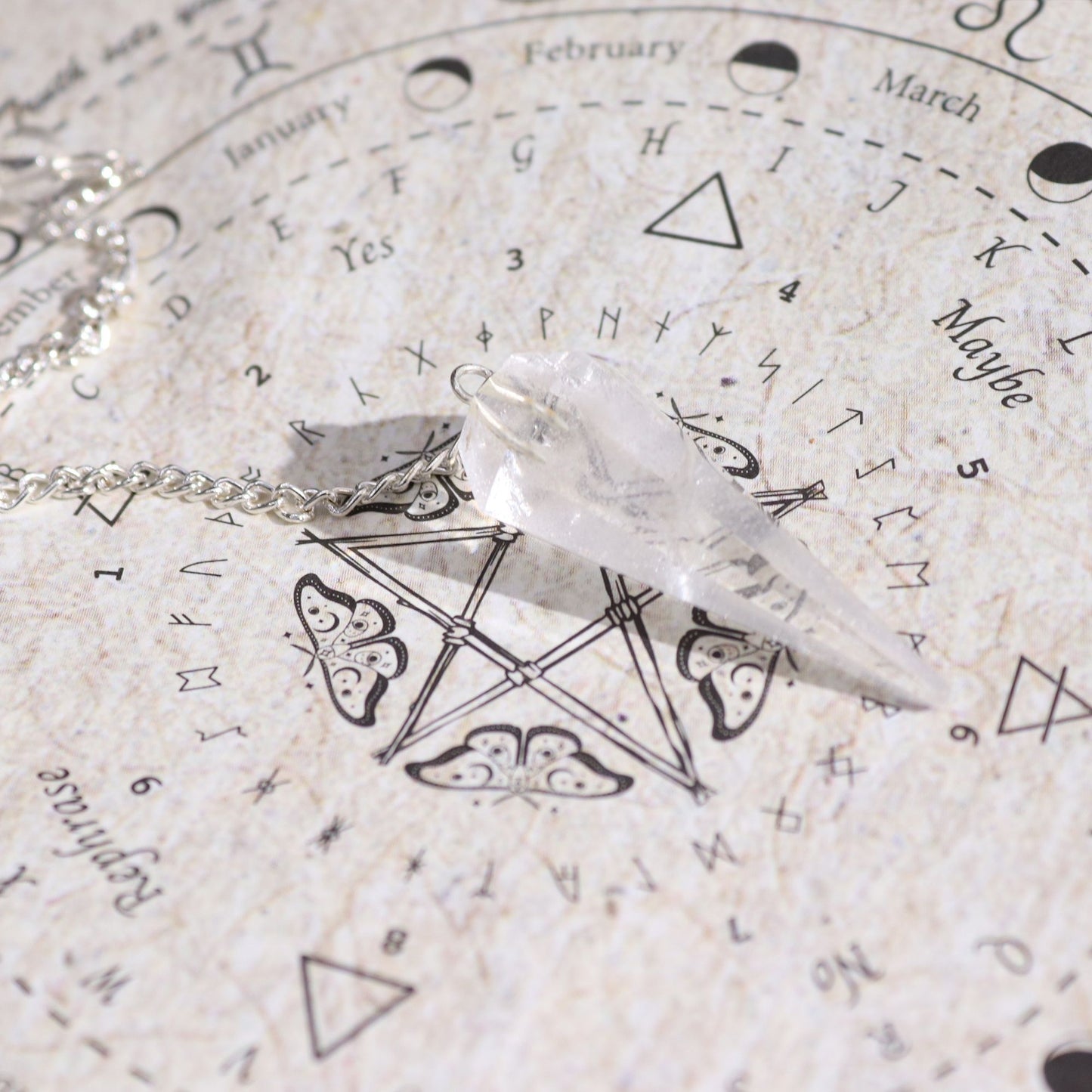 Bergkristall-Pendel auf einer Pendeltafel mit astrologischen Symbolen.