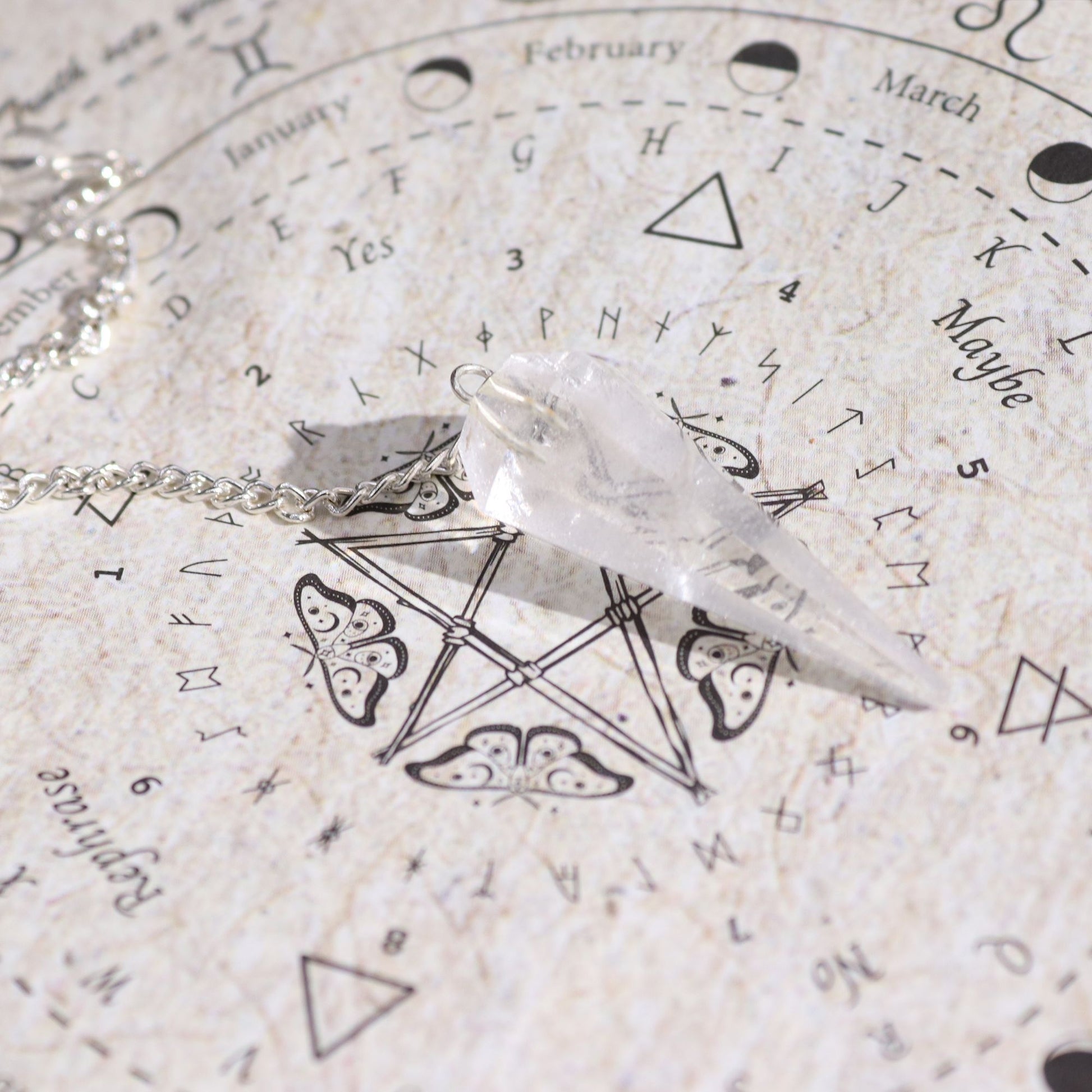 Bergkristall-Pendel auf einer Pendeltafel mit astrologischen Symbolen.