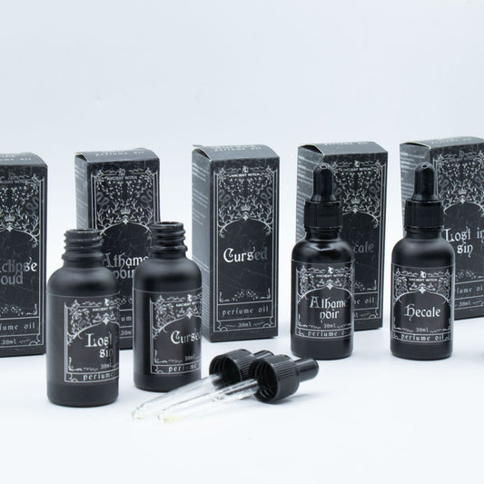 Black bottles of Ancient Witch perfume oil with ornate labels, including one for Hecate.
