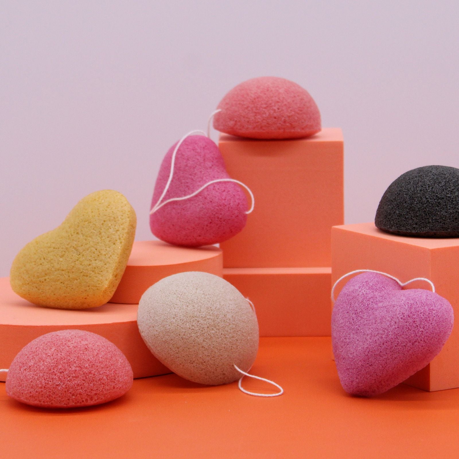 Konjac heart sponges in various colors are arranged on orange blocks.