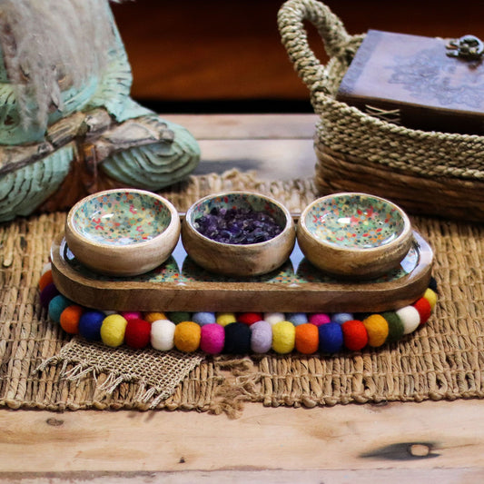 Multi-colored felt ball oval mat with a woven texture.