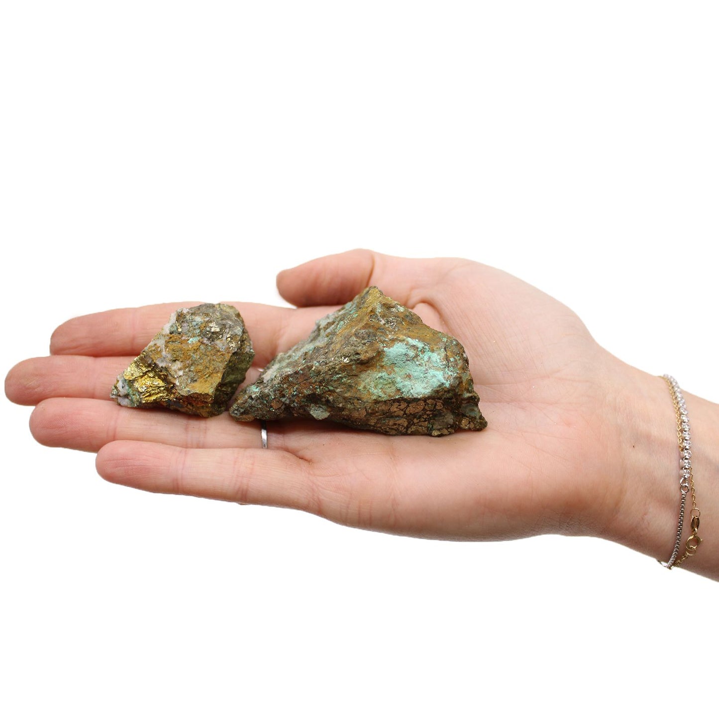 Hand hält zwei rohe Chalkopyrit-Steine mit goldenem Glanz und grünen Verfärbungen.
