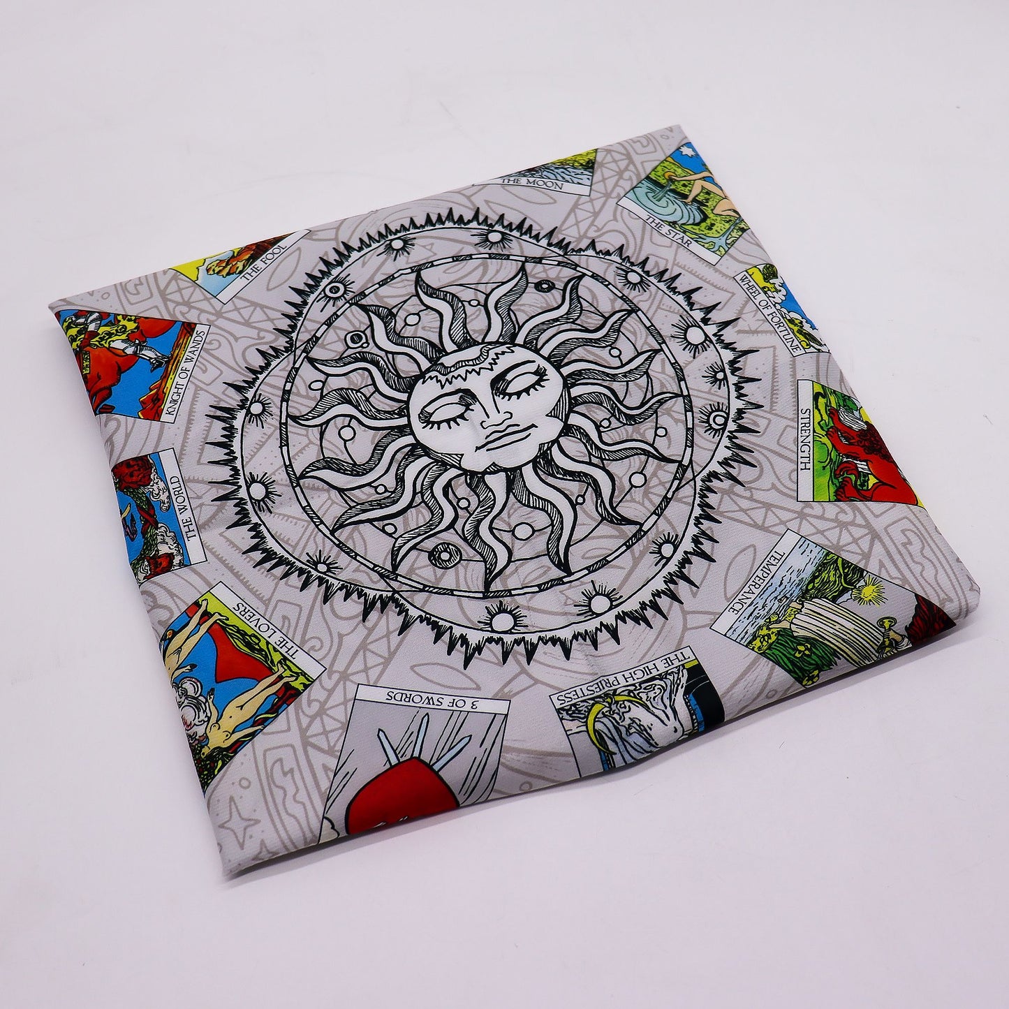 A grey tarot cloth with a central sun design and various tarot cards around the border.